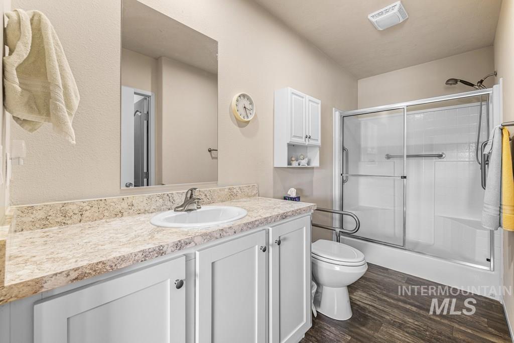 Bathroom featuring vanity, a stall shower, and dark wood-style flooring