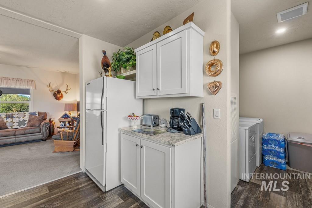 Kitchen featuring light countertops, white cabinets, dark wood-type flooring, and freestanding refrigerator