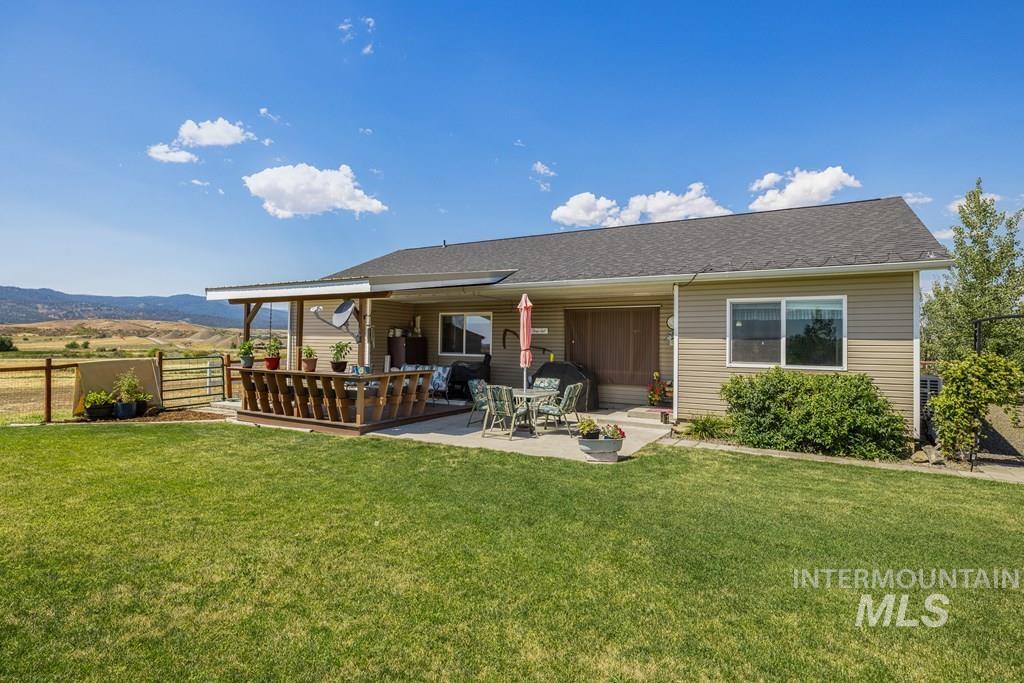 Rear view of property with a deck, a shingled roof, and a patio