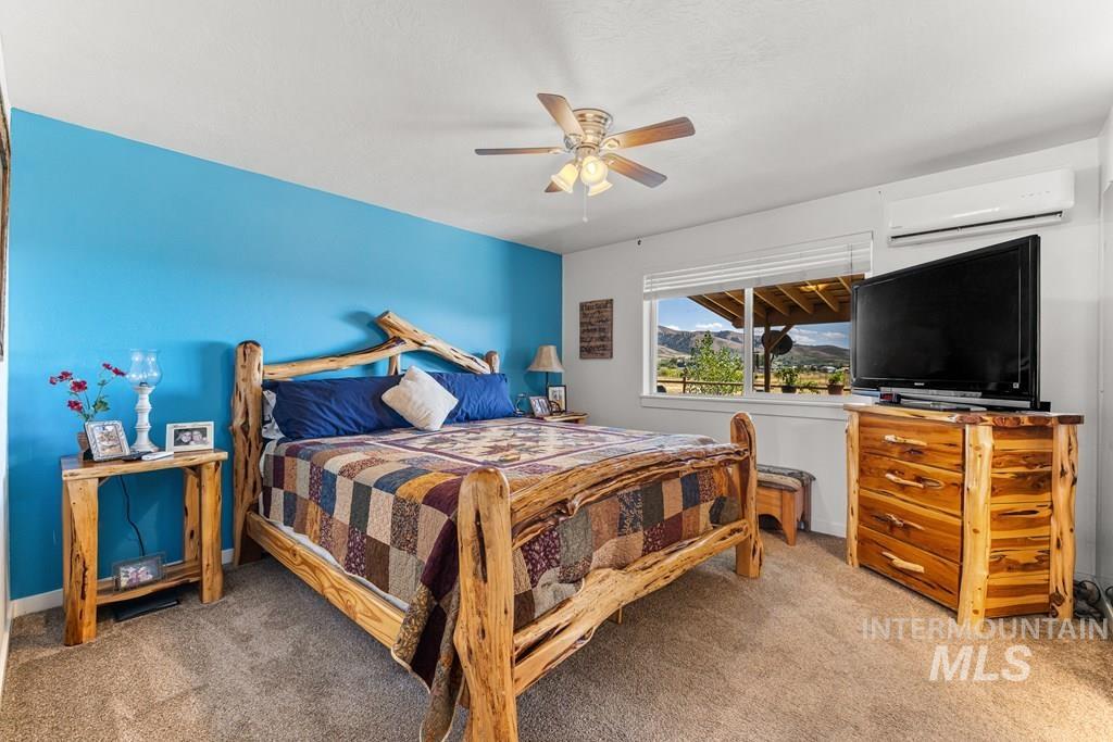 Carpeted bedroom featuring a wall mounted AC and a ceiling fan