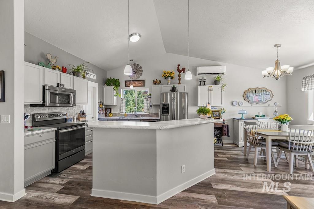Kitchen featuring stainless steel appliances, vaulted ceiling, backsplash, dark wood-style flooring, and white cabinets