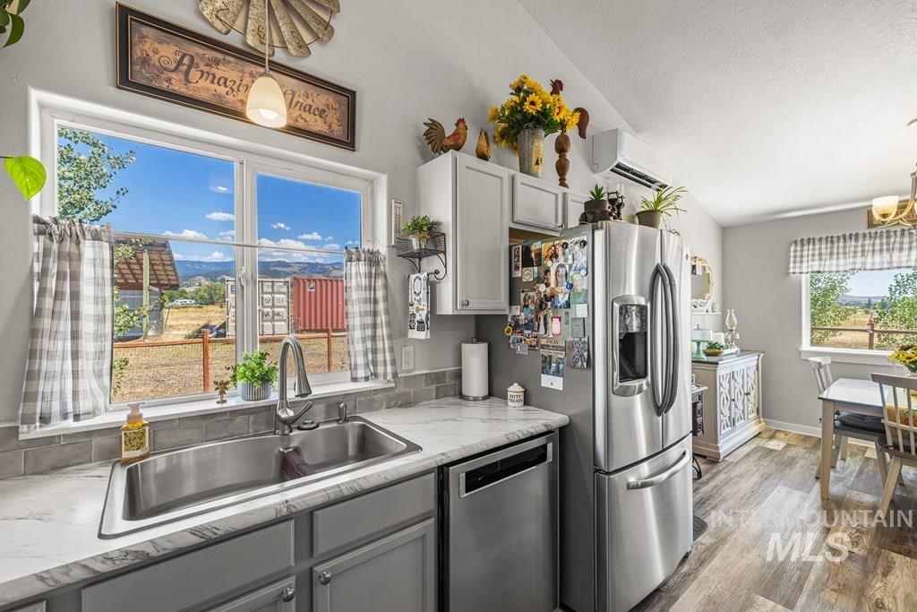 Kitchen featuring light countertops, pendant lighting, gray cabinets, stainless steel dishwasher, and light wood finished floors