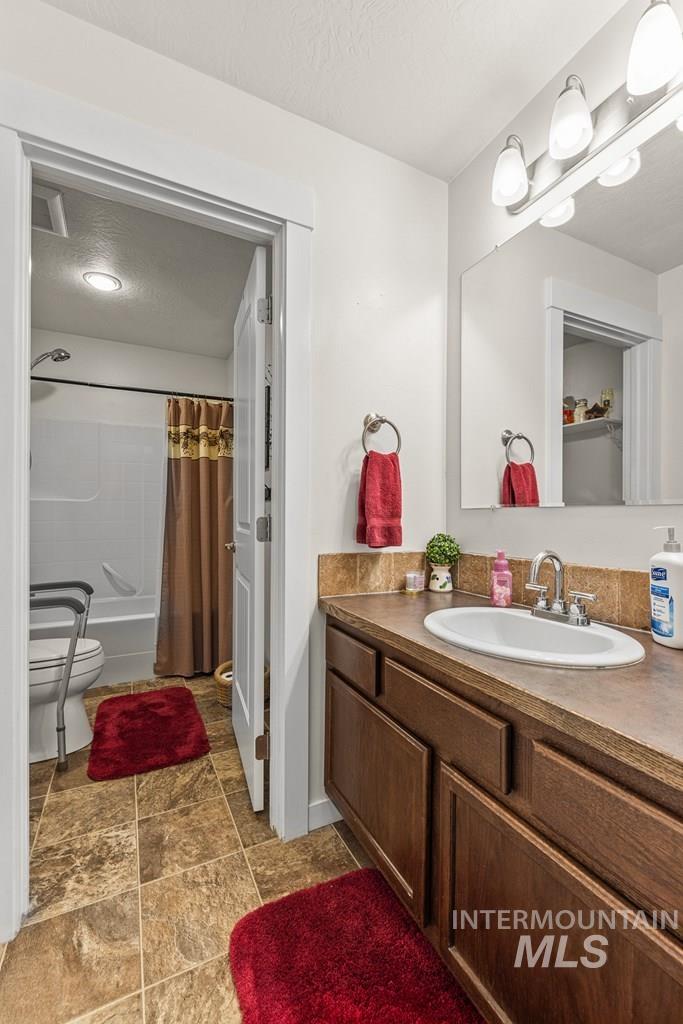 Bathroom with shower / tub combo with curtain, vanity, and a textured ceiling