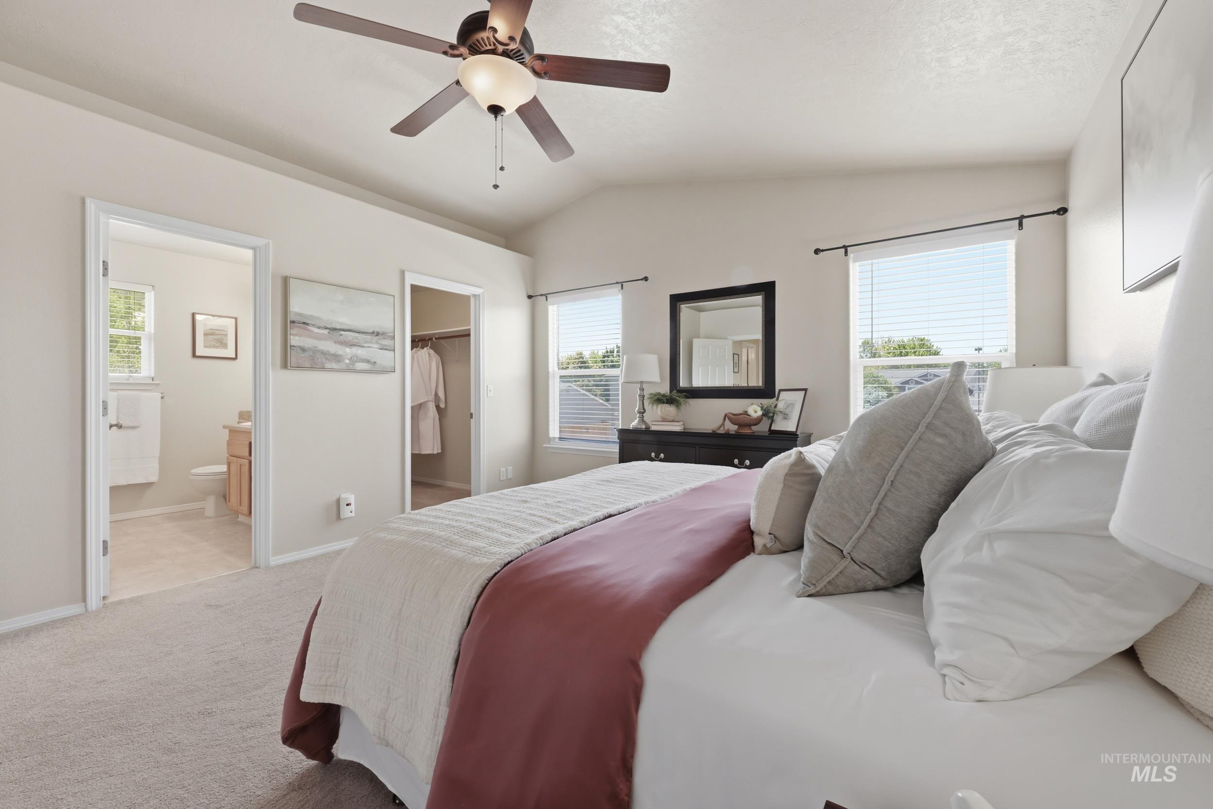 Carpeted bedroom featuring vaulted ceilings and a ceiling fan with integrated lighting