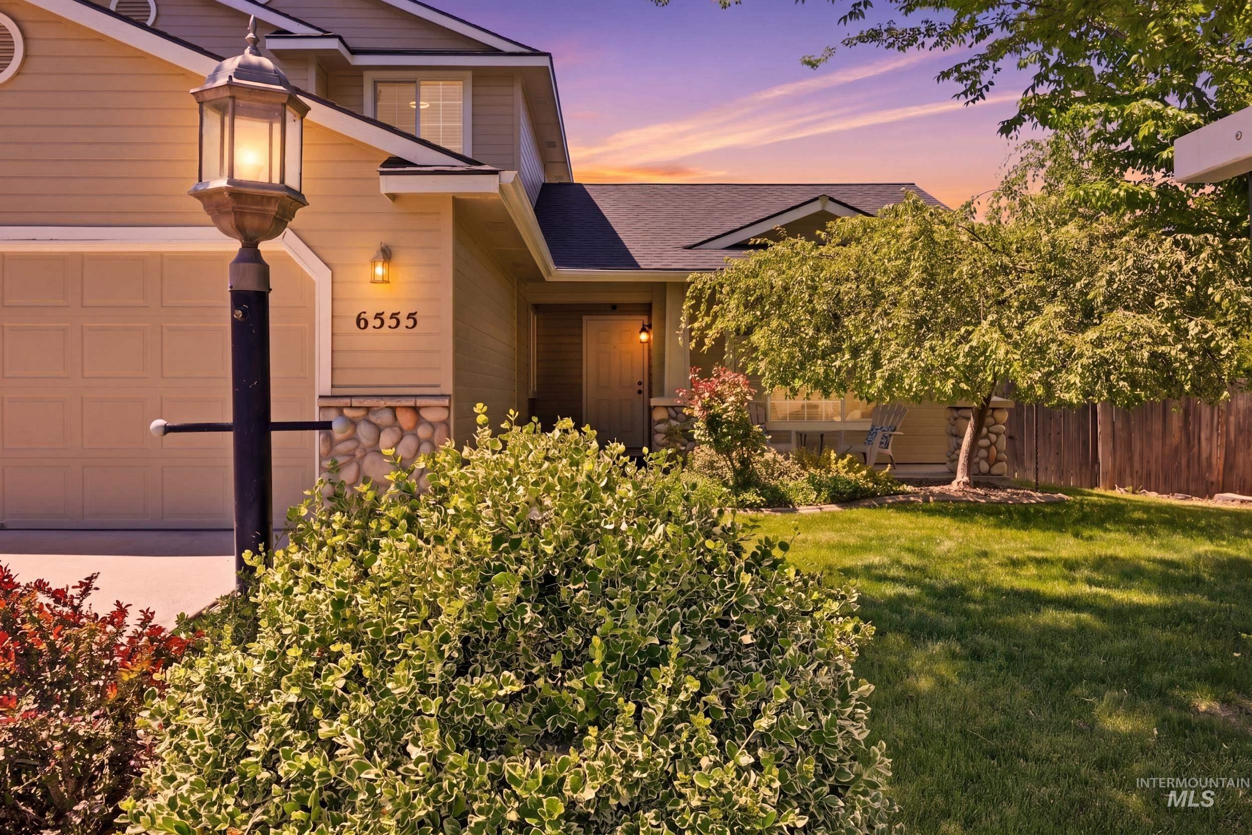 Exterior featuring a neutral siding facade, stone accents, a two-car garage, and a covered front entry