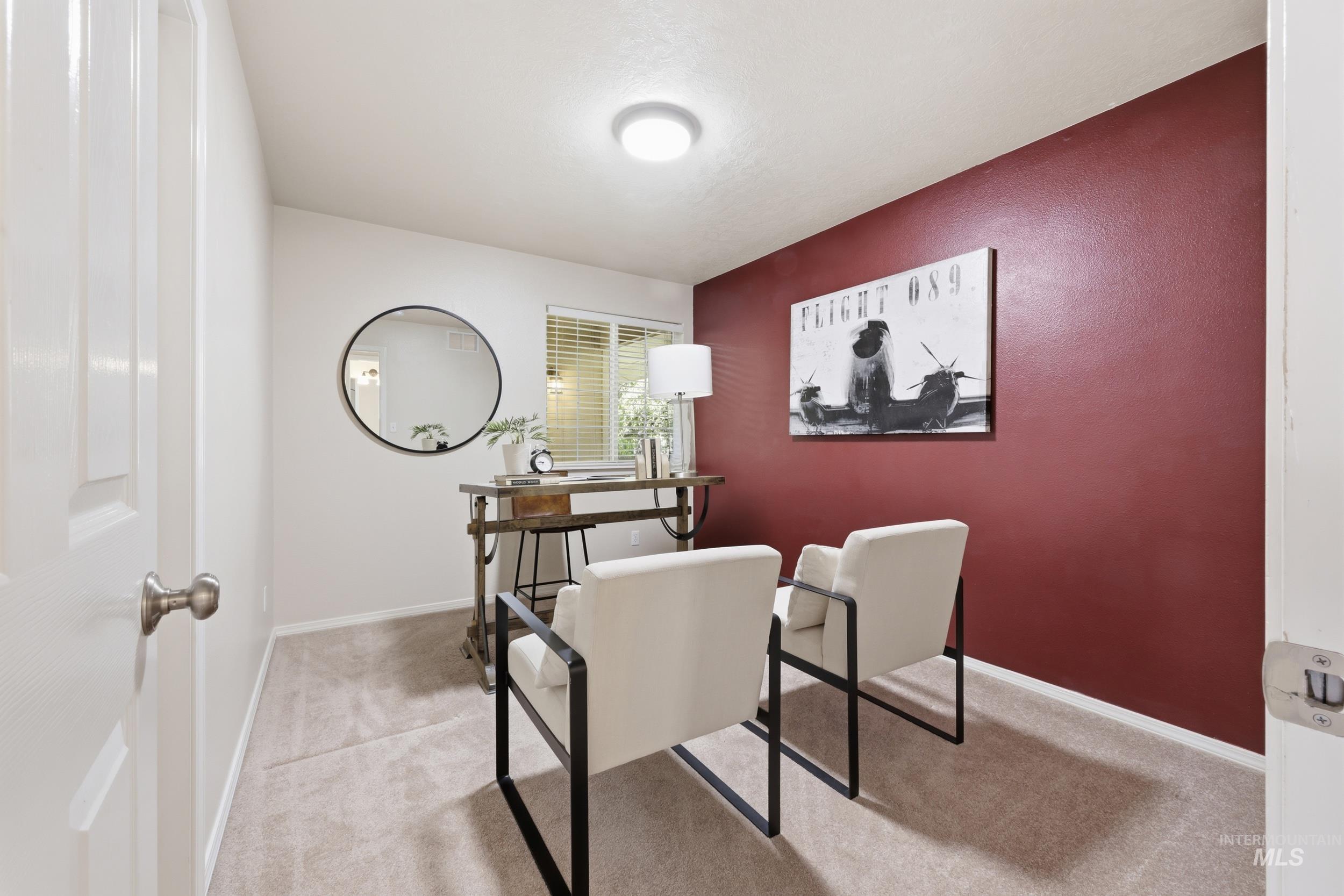 Room featuring light-colored carpeting, a window with horizontal blinds, and a contrasting accent wall