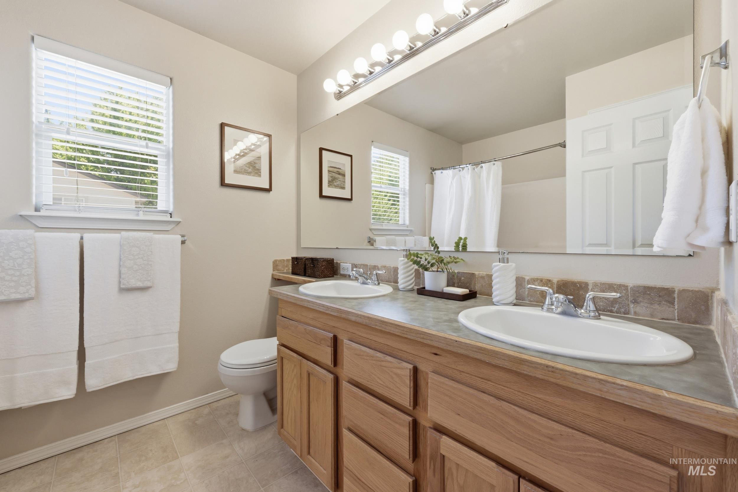 Double vanity with wood-finish cabinetry, integrated sinks, and a stone-look countertop