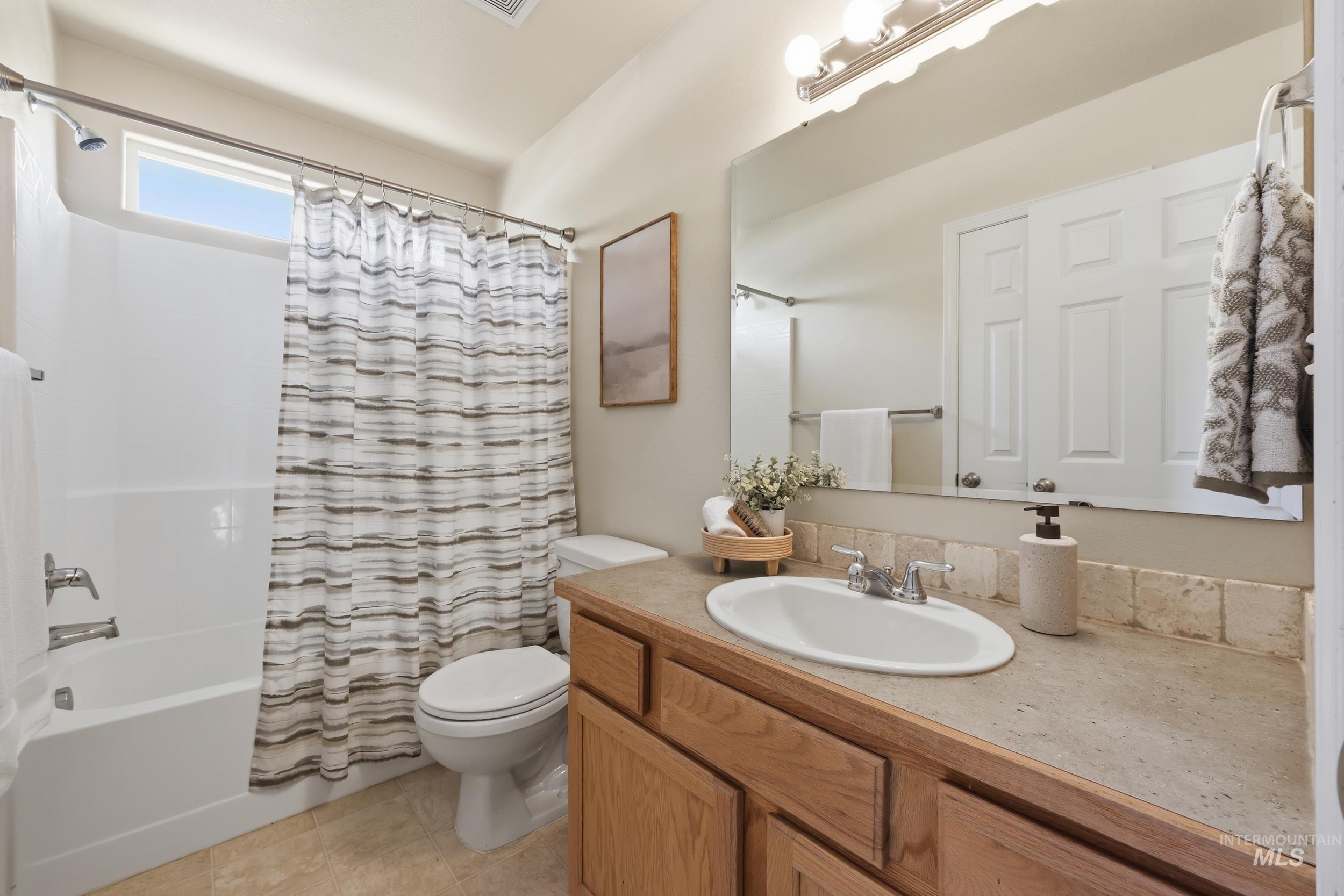 Bathroom featuring a full vanity with wood-finish cabinetry, an integrated sink, and a large mirror