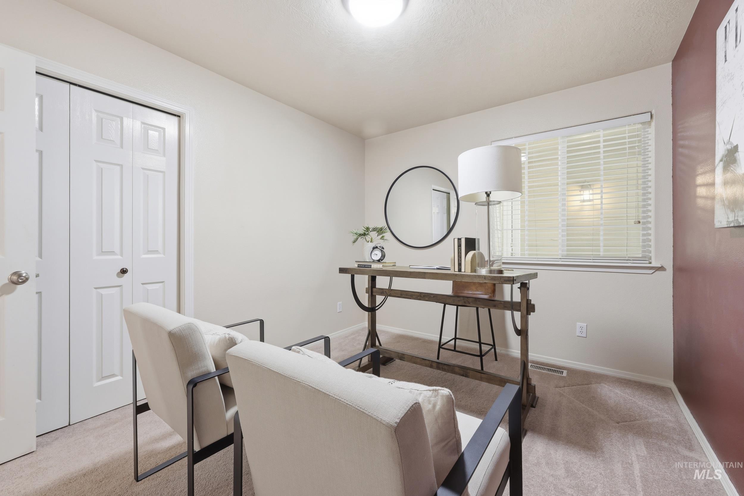 Neutral wall tones with a deep red accent wall, carpeted flooring, and a window with horizontal blinds