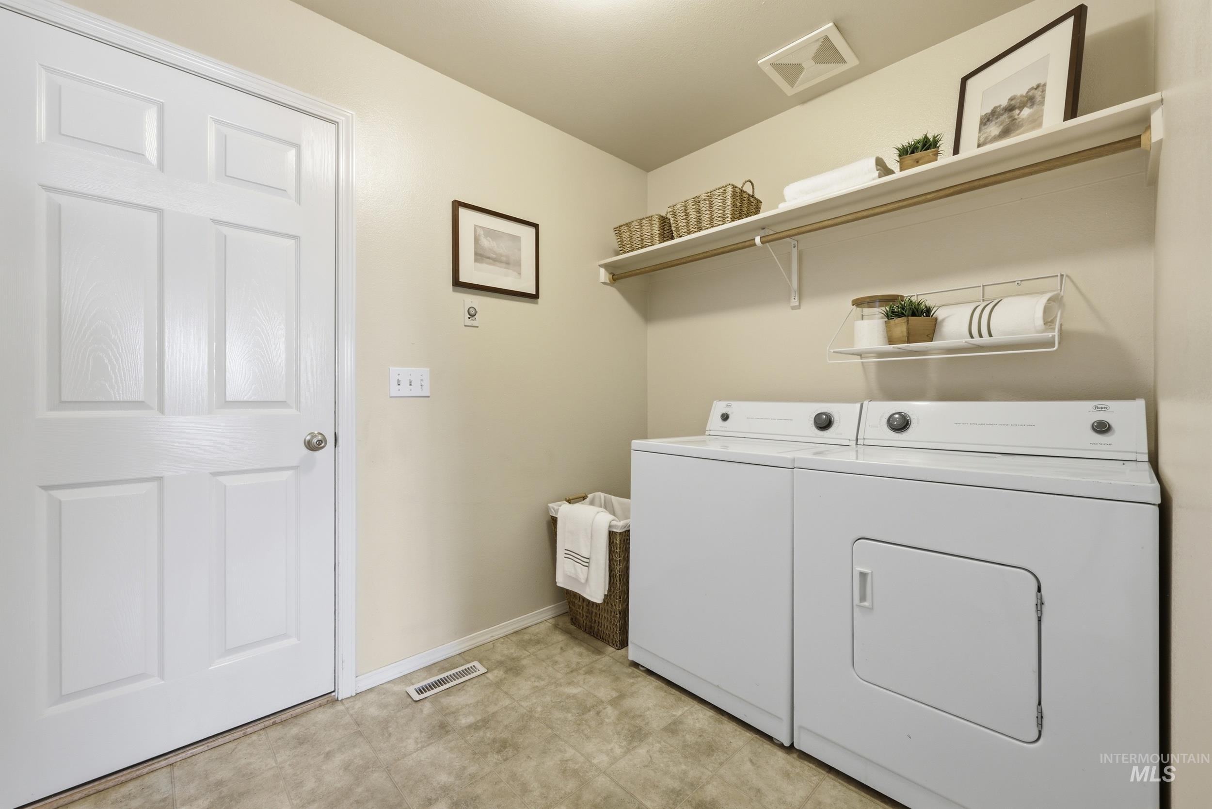 Dedicated laundry area featuring a white six-panel door, light-toned wall paint, and durable floor tile