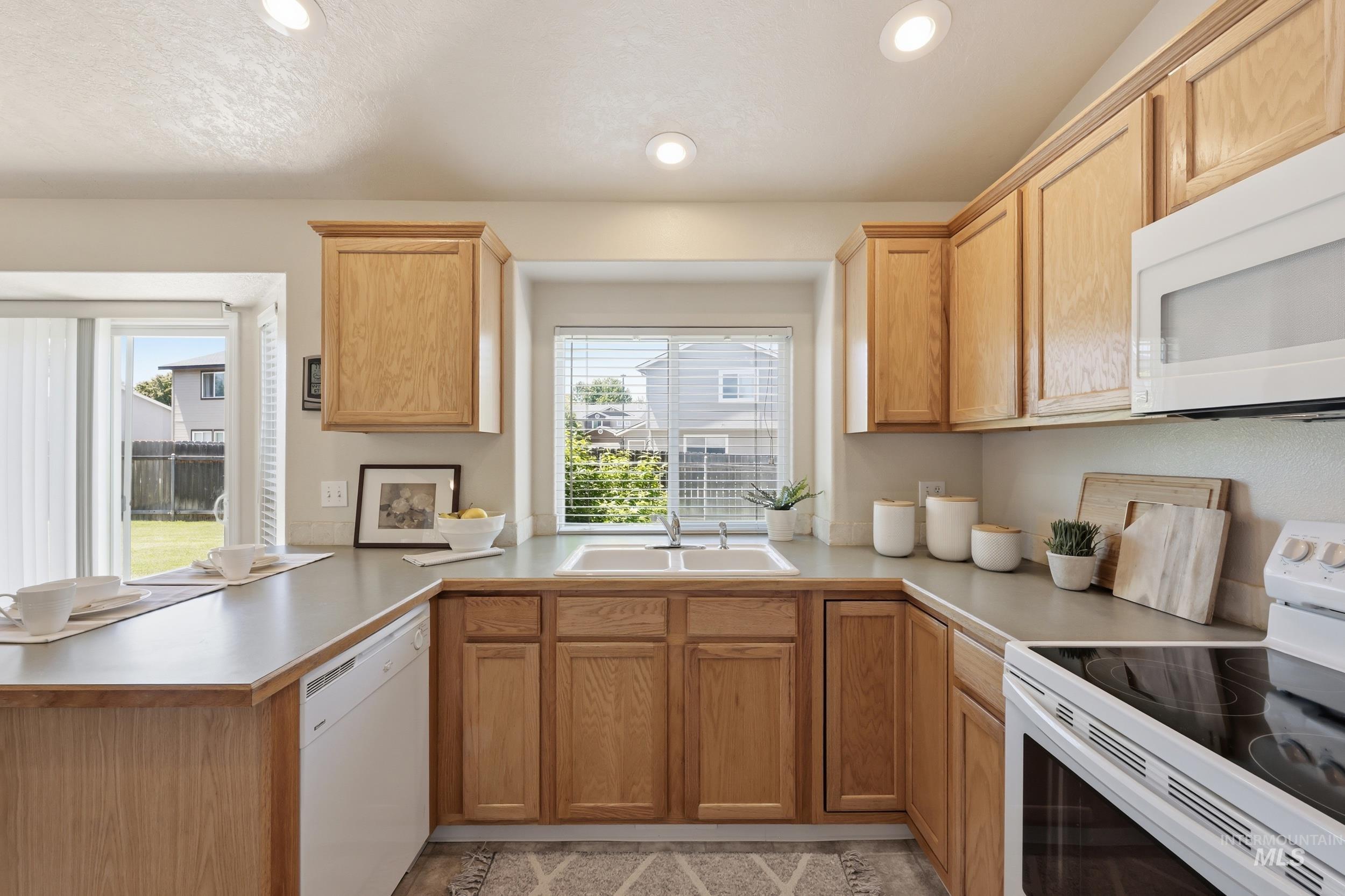 Kitchen featuring light wood cabinetry, a double basin sink, and recessed lighting