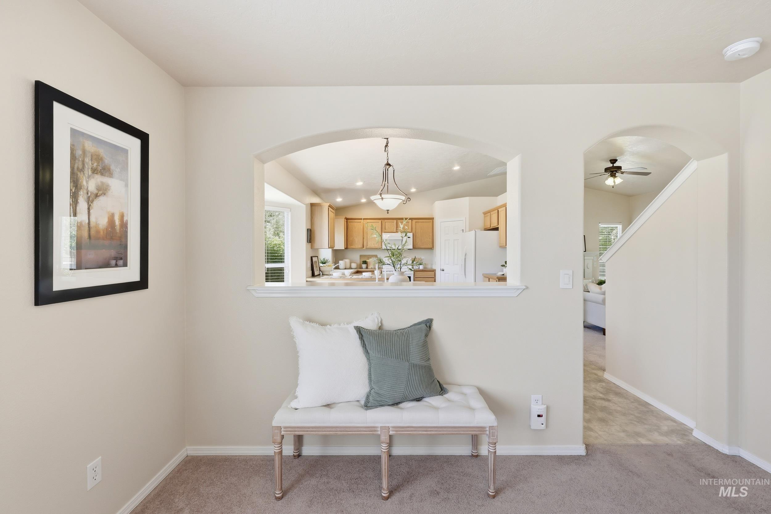 Archway opening into a kitchen featuring wood cabinetry and a pendant light fixture