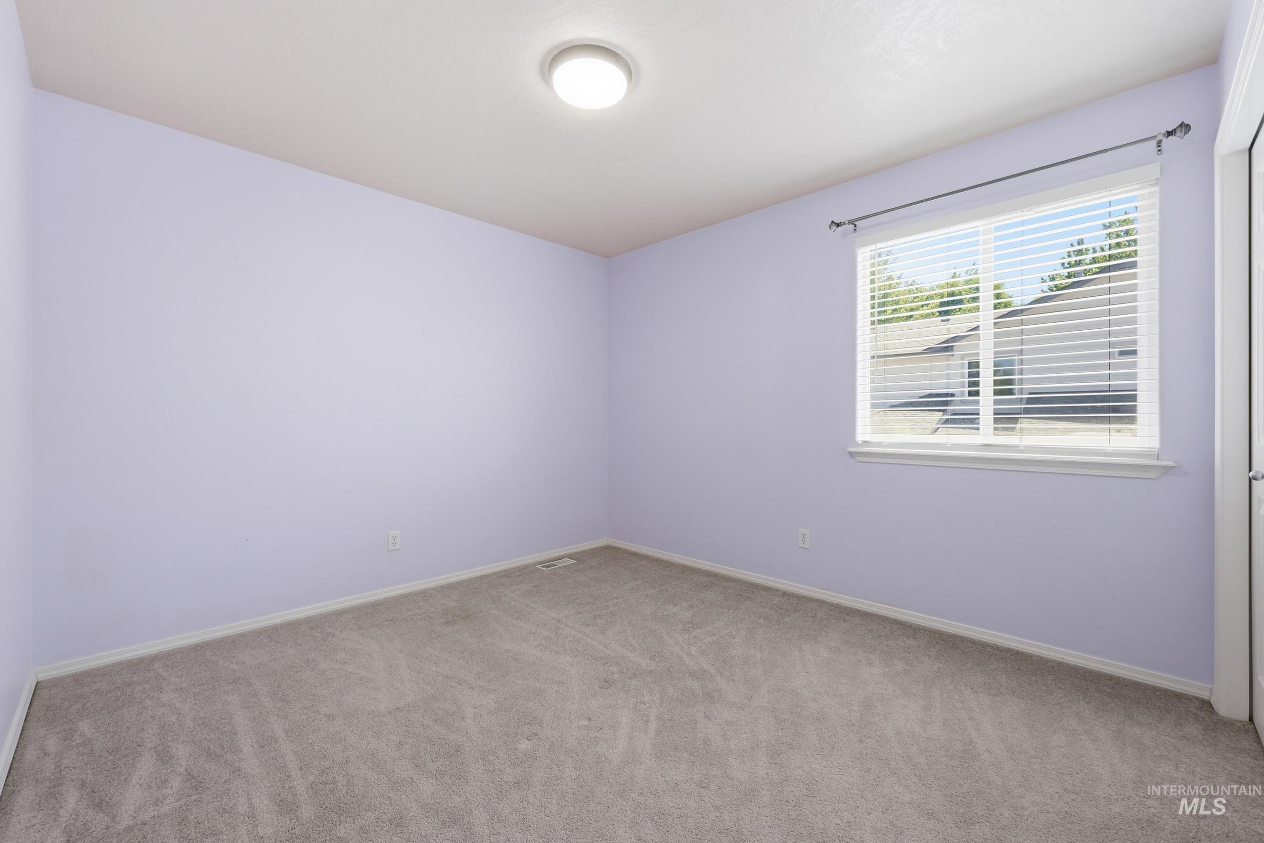 Room featuring soft violet walls and light gray carpet