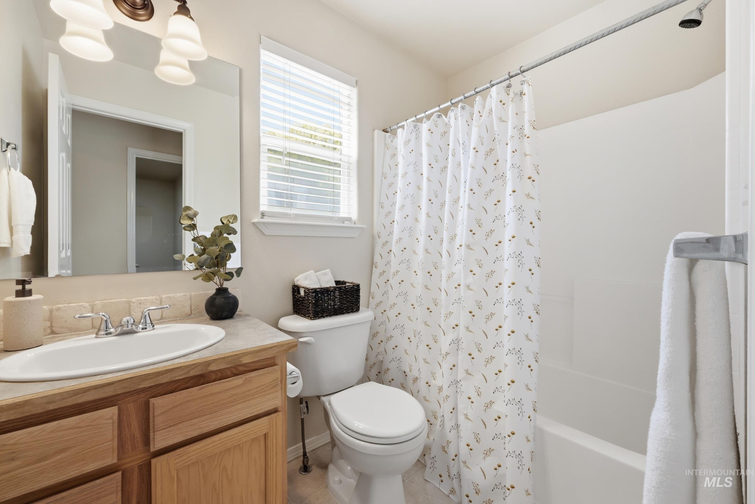 Full bathroom featuring a single vanity with wood cabinetry, an oval undermount sink, and a light-toned countertop