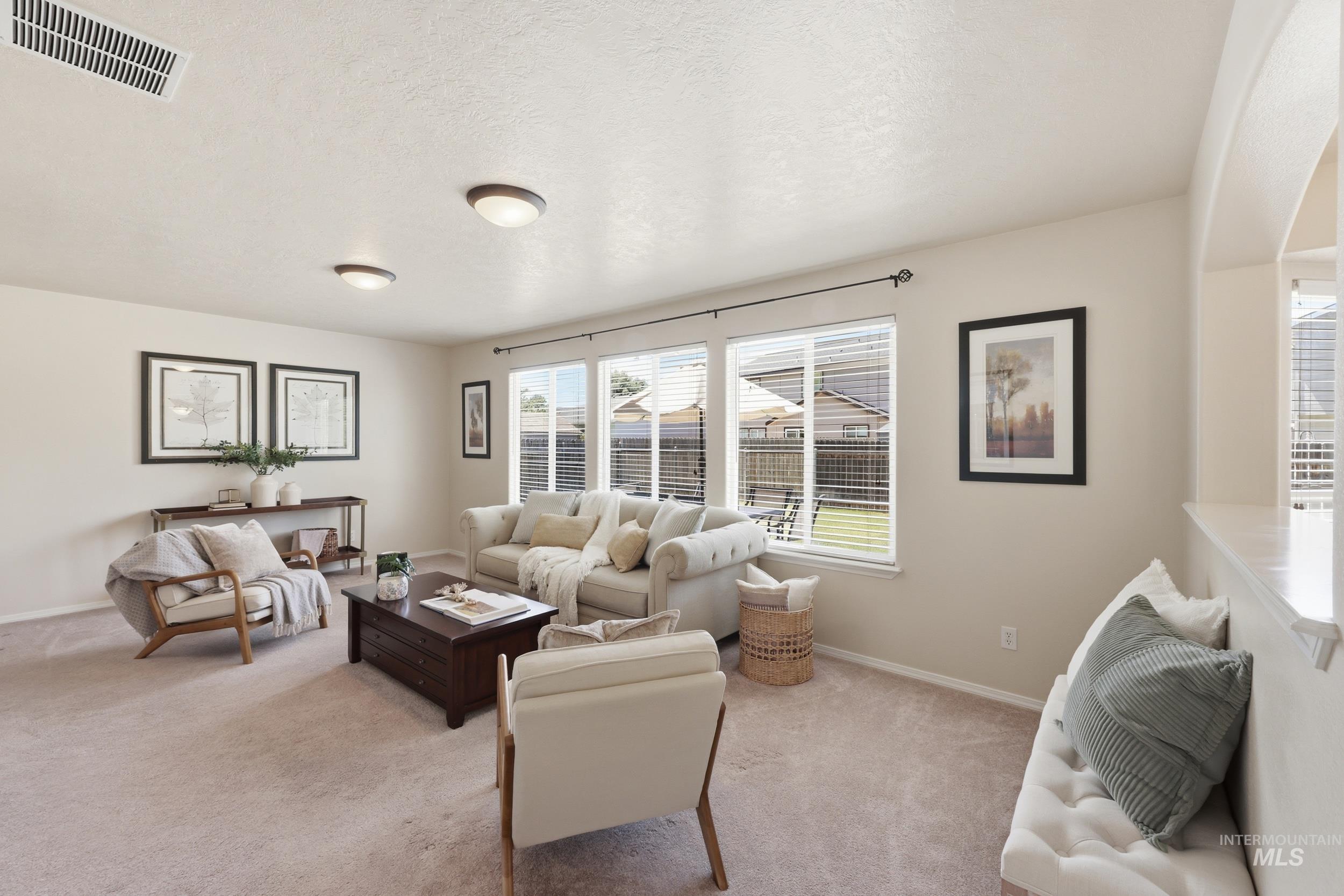 Spacious living room featuring multiple windows, recessed lighting, and neutral-toned carpeting