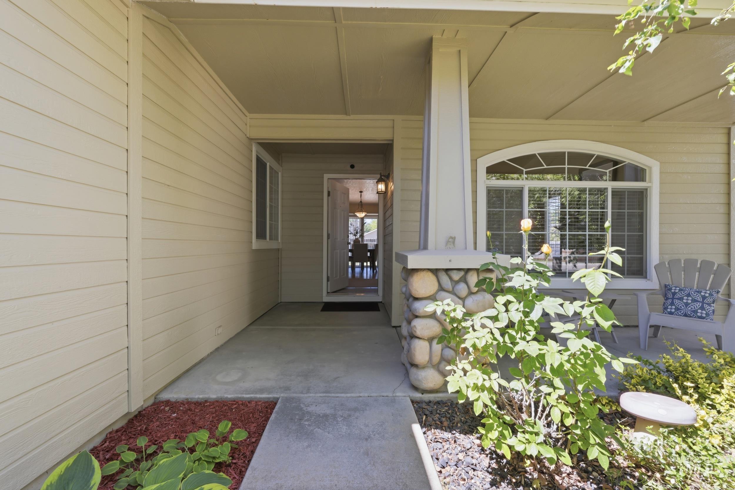 Front entry featuring a covered porch, stone column base, horizontal siding, and an arched window with grilles