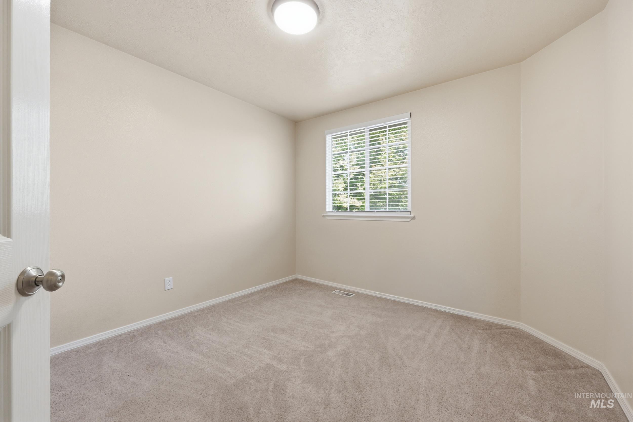 Bedroom featuring a single window with blinds, neutral carpeting, light-toned walls, and a ceiling-mounted light fixture