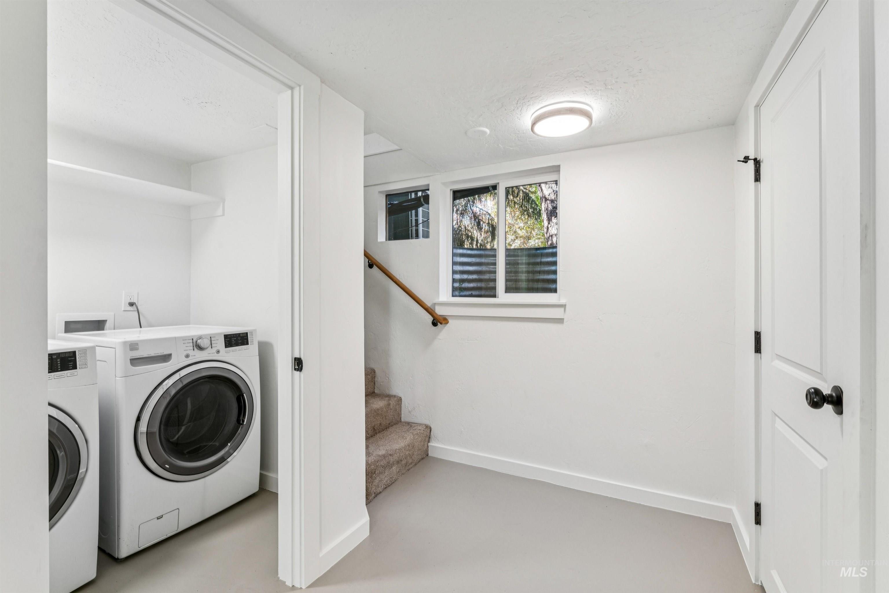 Laundry room featuring finished concrete floors, a textured ceiling, and washing machine and dryer