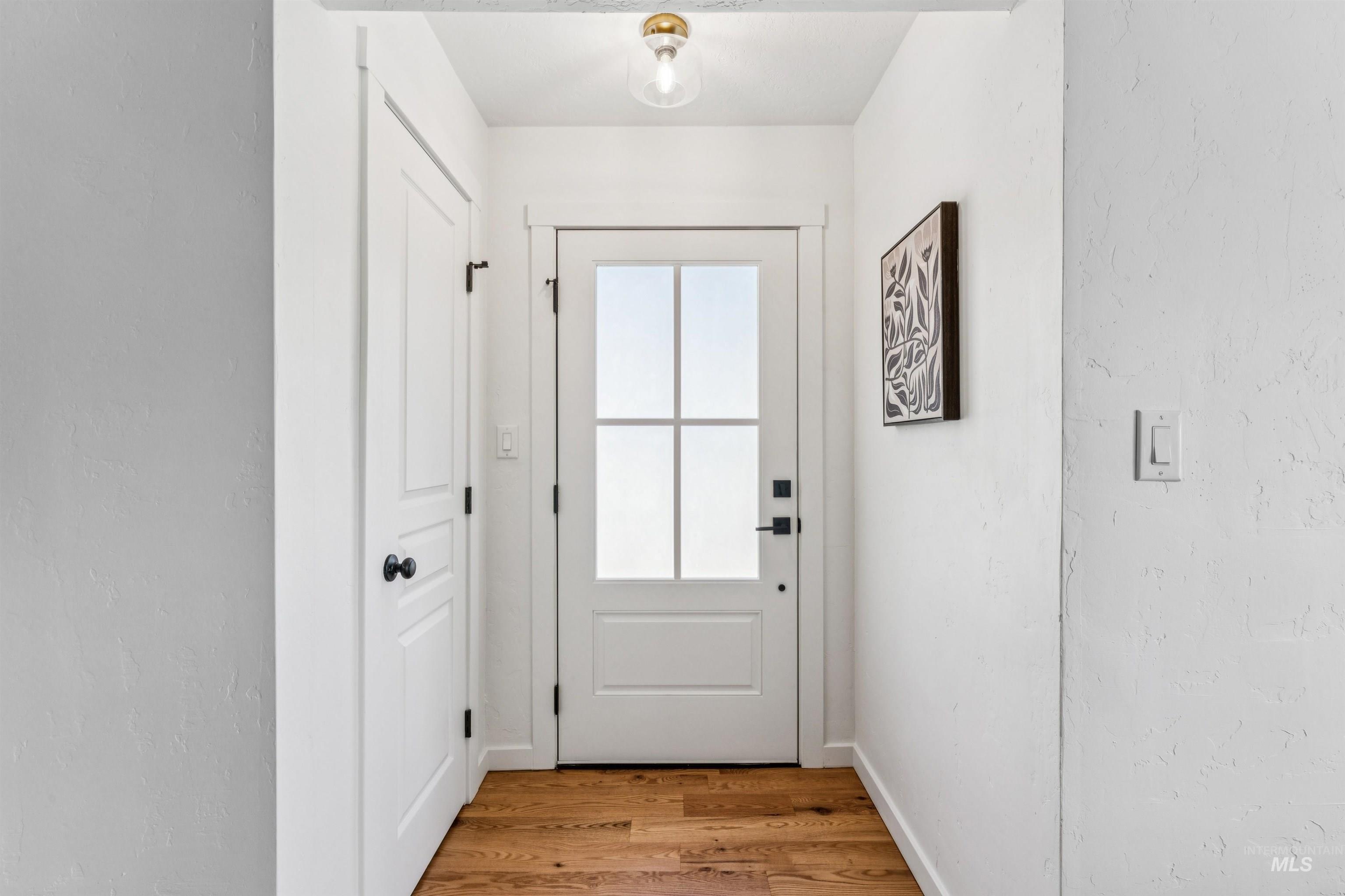 Doorway to outside featuring wood finished floors and a textured wall
