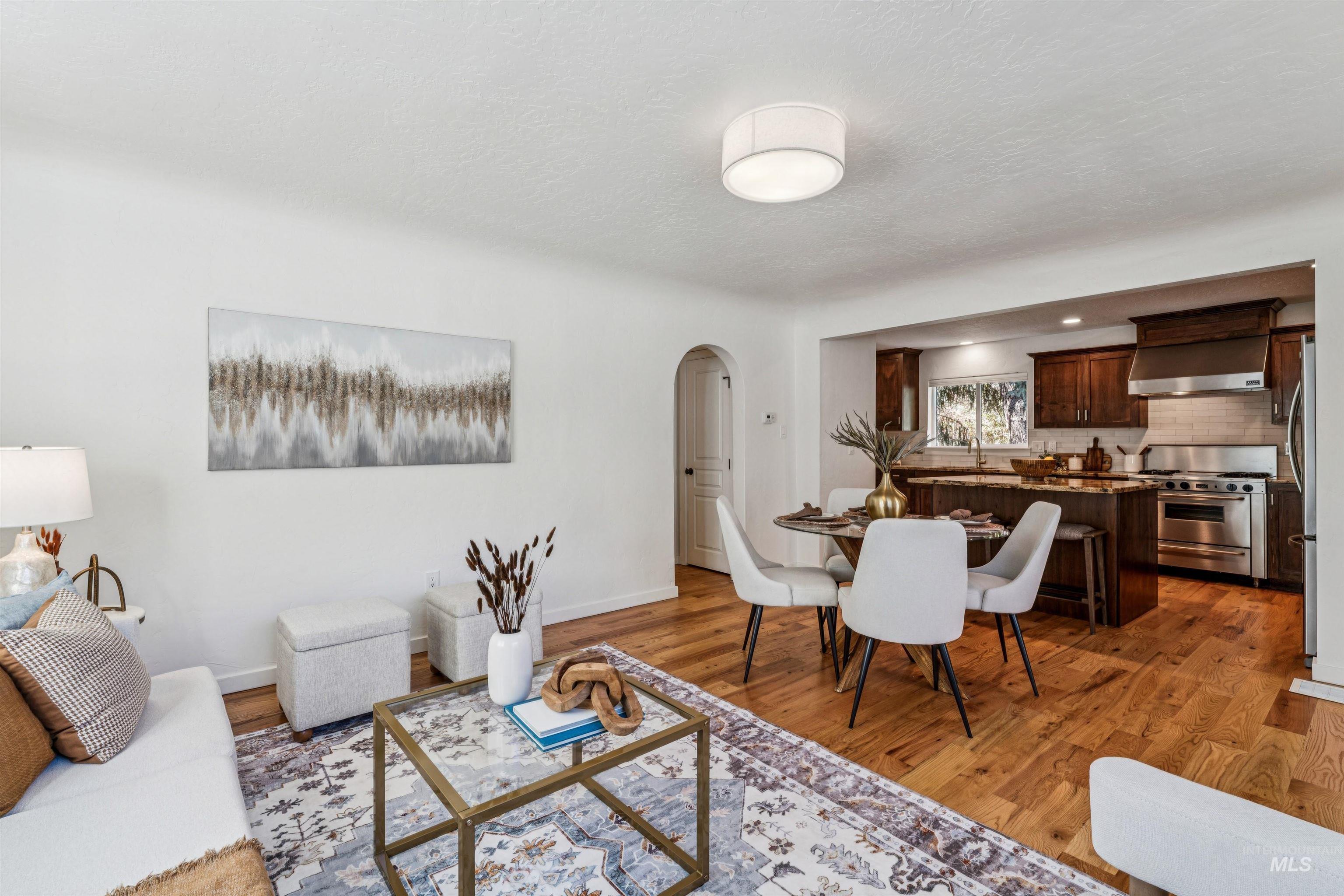 Great room featuring arched walkways, light wood finished floors, and a textured ceiling