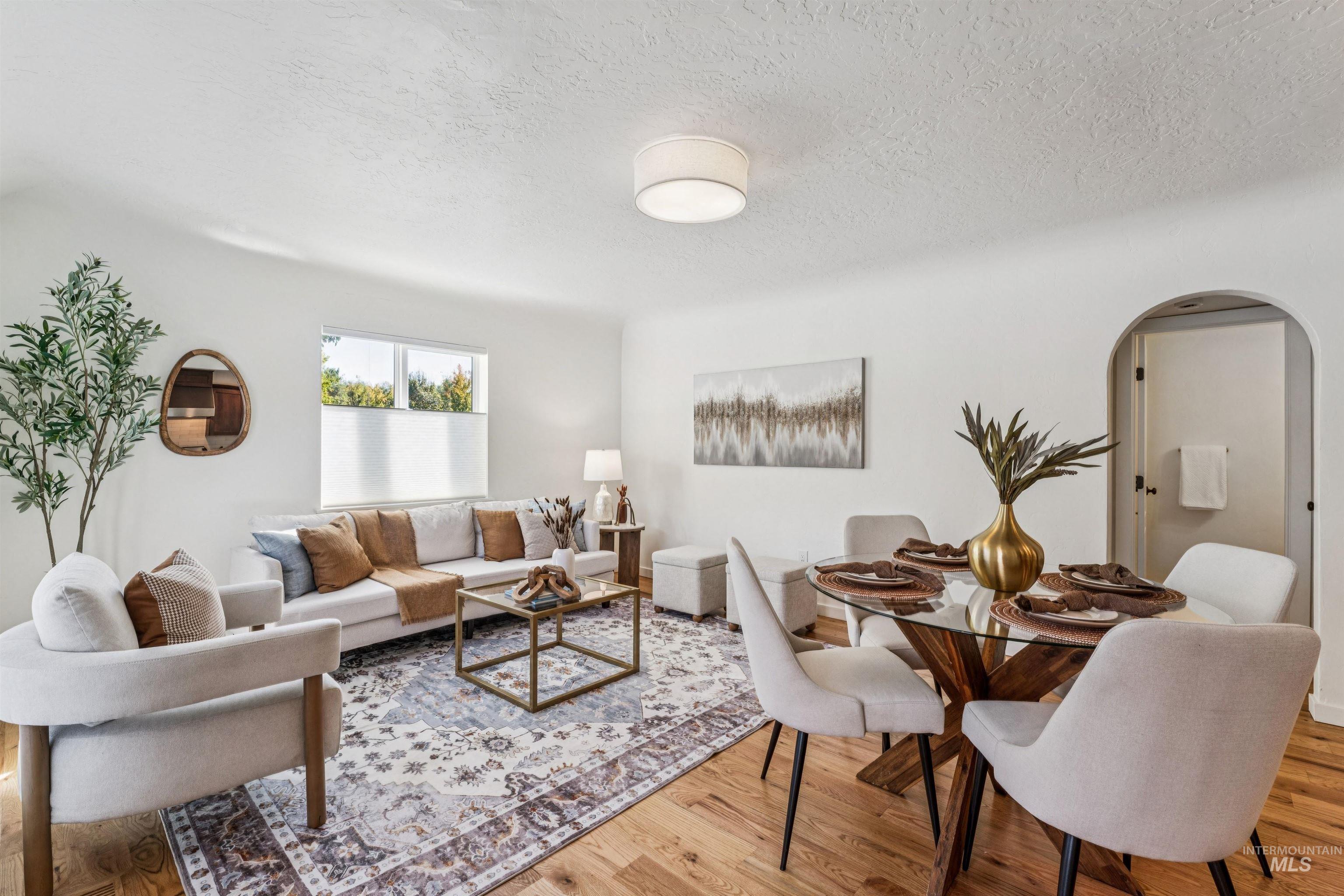 Great room area with arched walkways, a textured ceiling, and light wood-type flooring