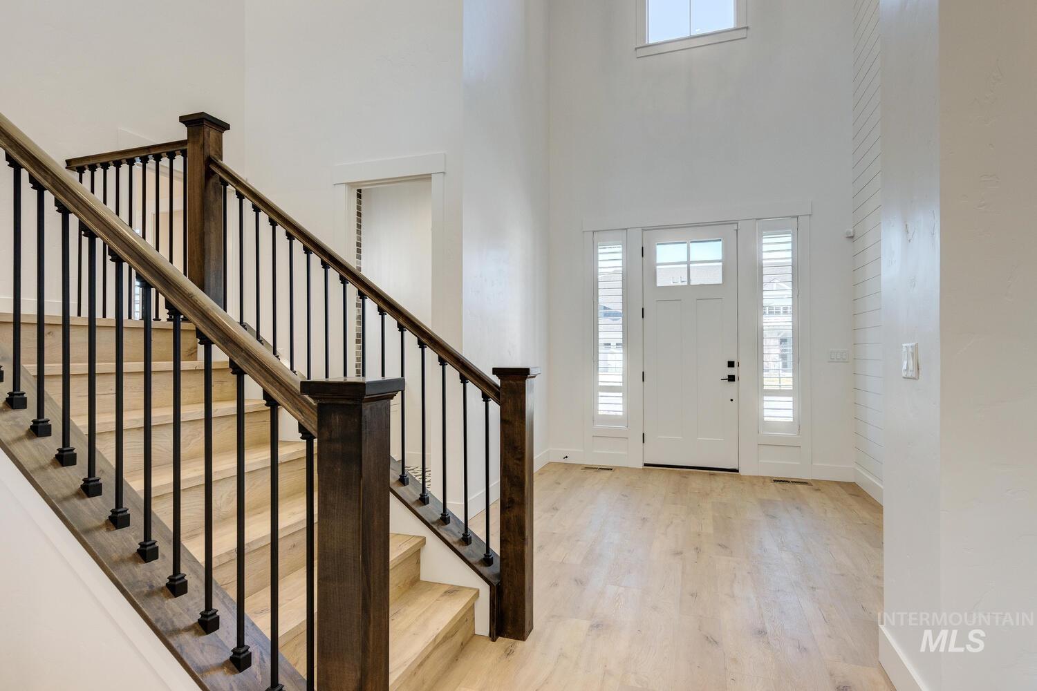 Foyer entrance featuring light wood finished floors, stairs, and a towering ceiling