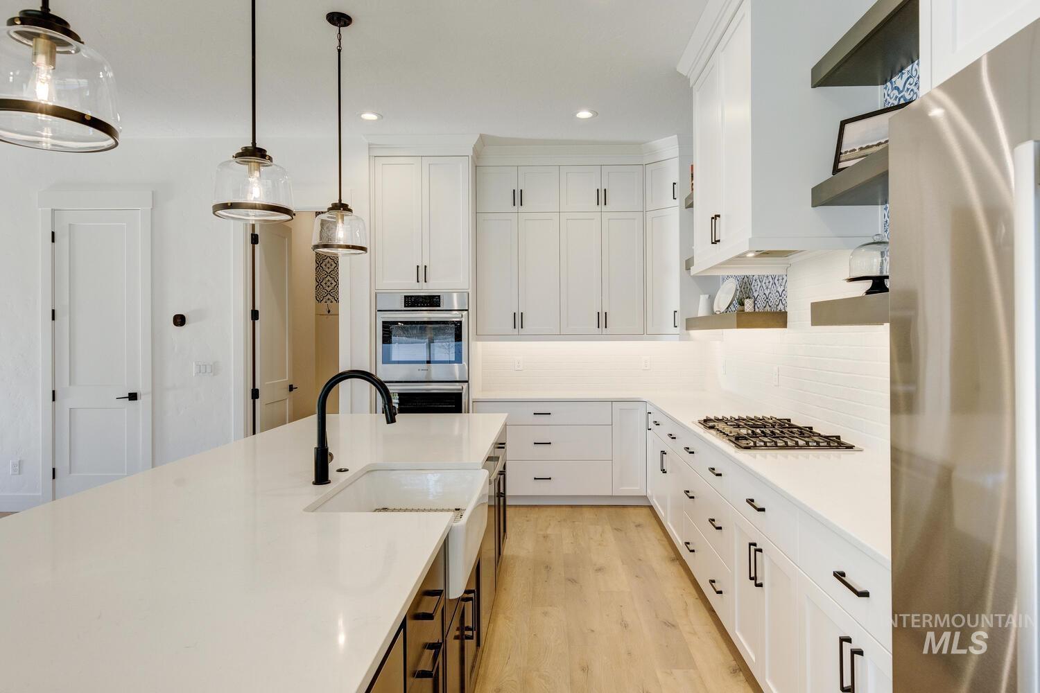 Kitchen featuring appliances with stainless steel finishes, white cabinetry, decorative light fixtures, backsplash, and recessed lighting