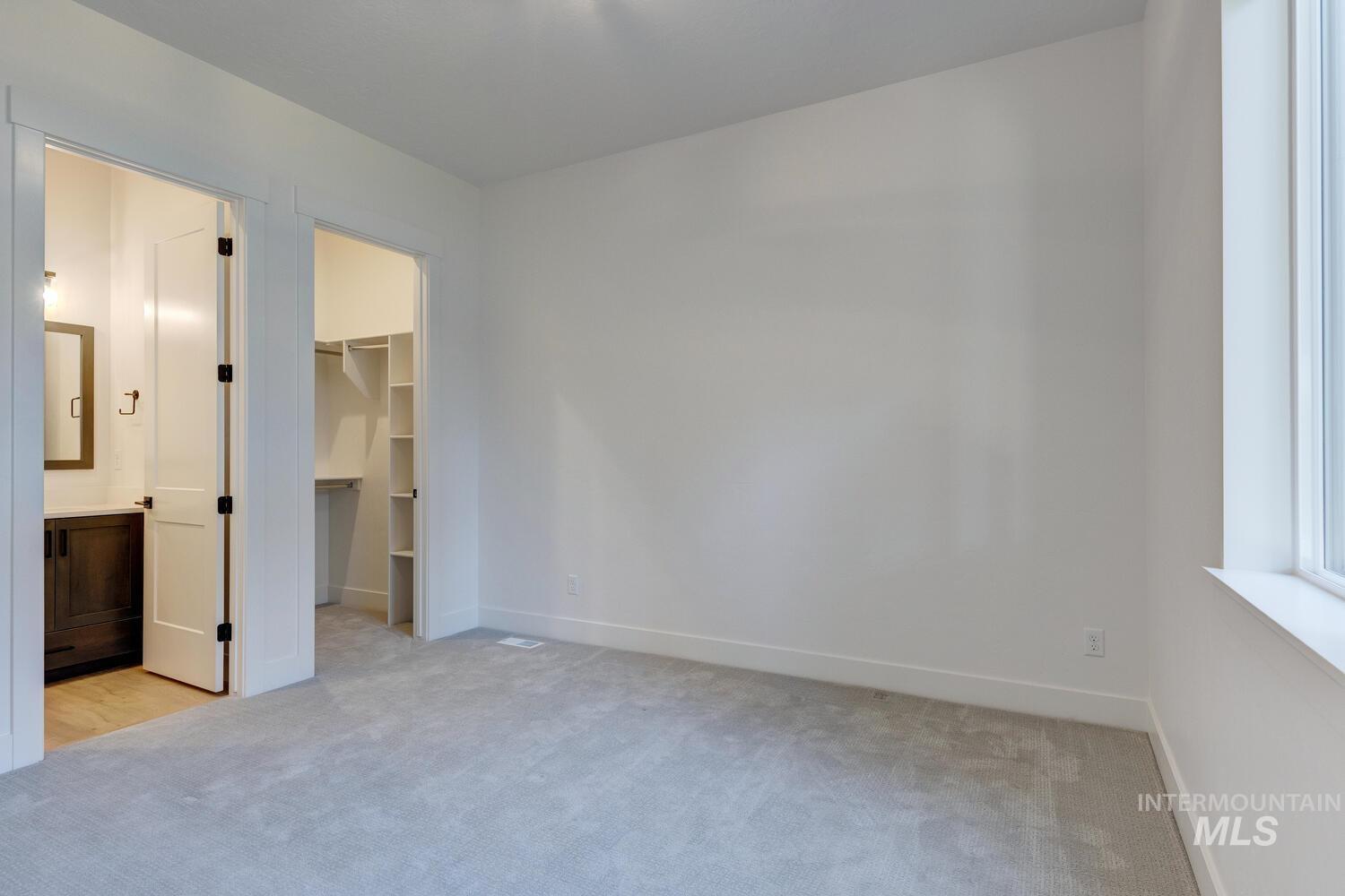 Unfurnished bedroom with light carpet, a walk in closet, and connected bathroom