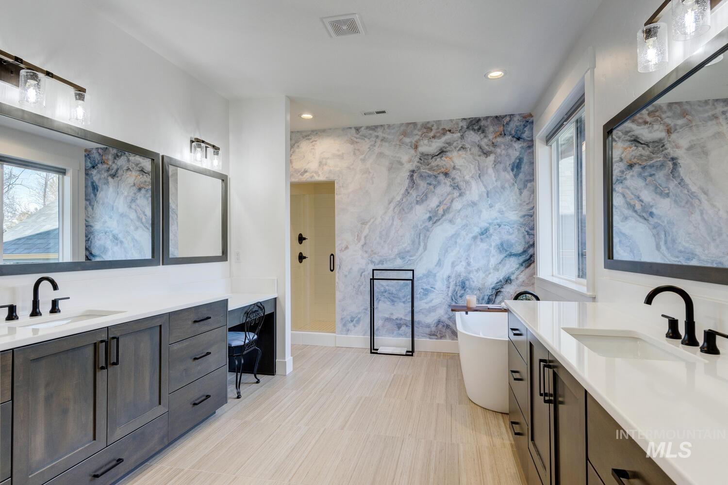 Full bathroom featuring two vanities, recessed lighting, a freestanding bath, and a stall shower
