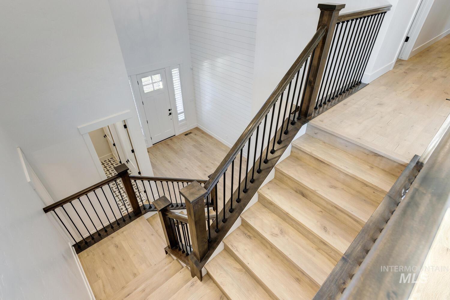 Staircase with a towering ceiling and wood-type flooring