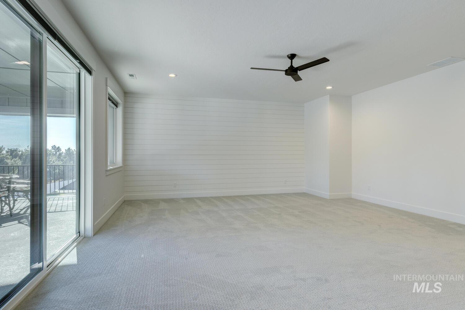 Spare room featuring wooden walls, light colored carpet, ceiling fan, and recessed lighting