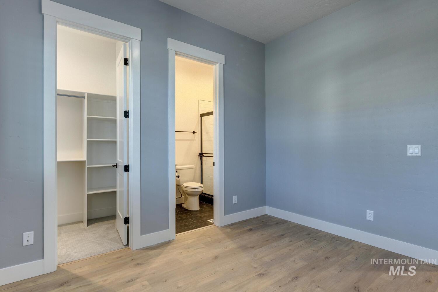 Unfurnished bedroom with a walk in closet and light wood-type flooring