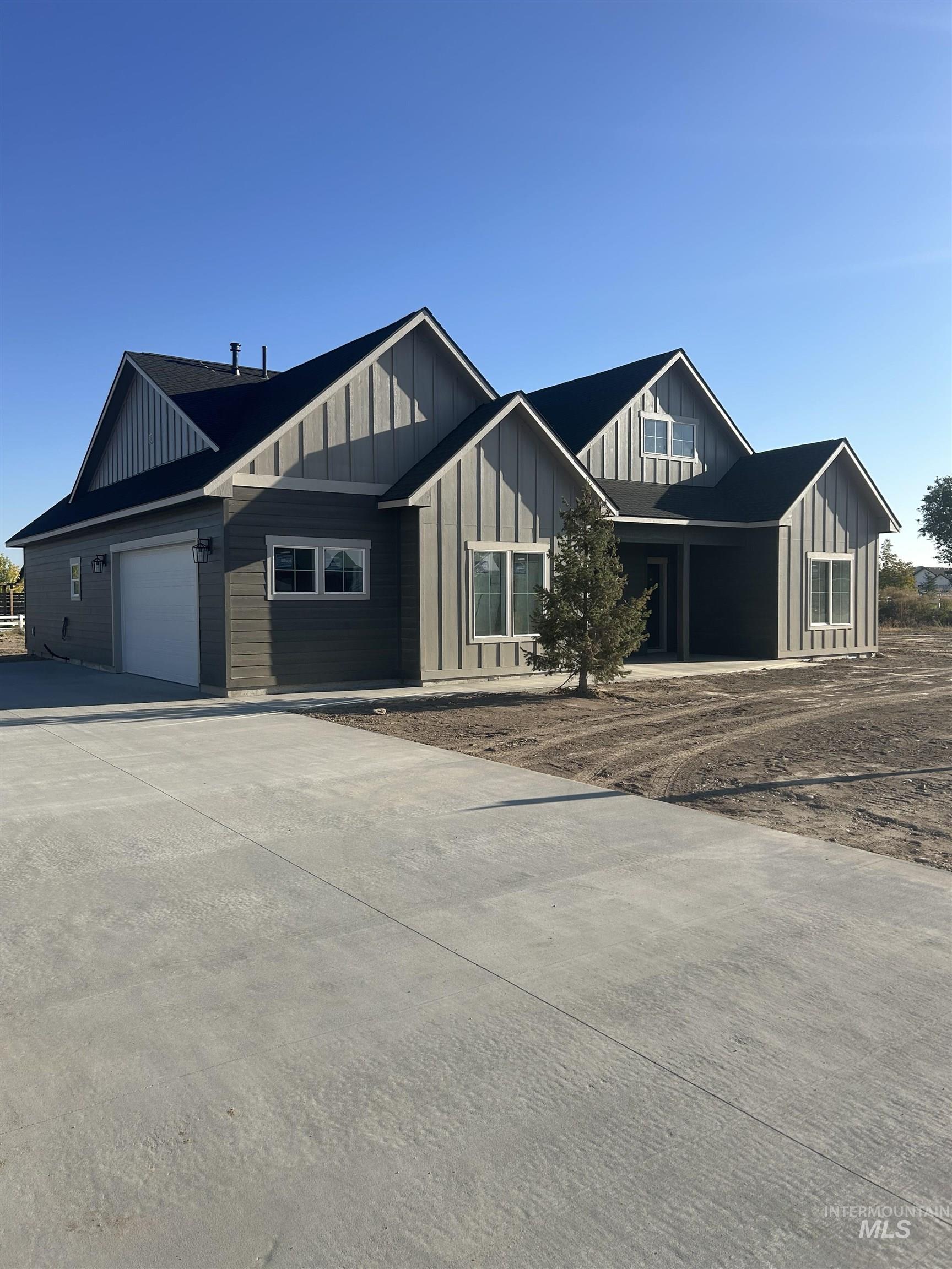 View of front of property with board and batten siding, concrete driveway, and an attached garage