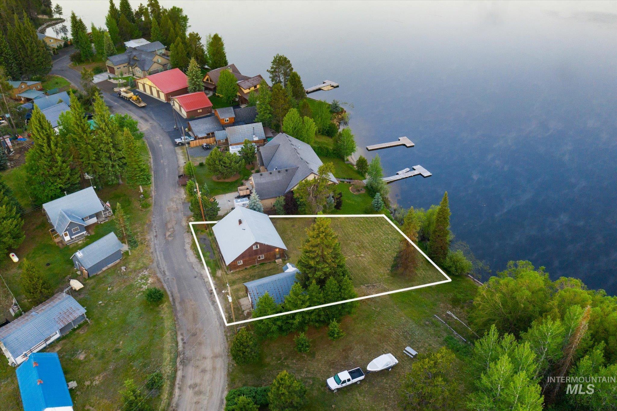 Waterfront property featuring a residential structure with a light-colored roof and an expansive grassy lot