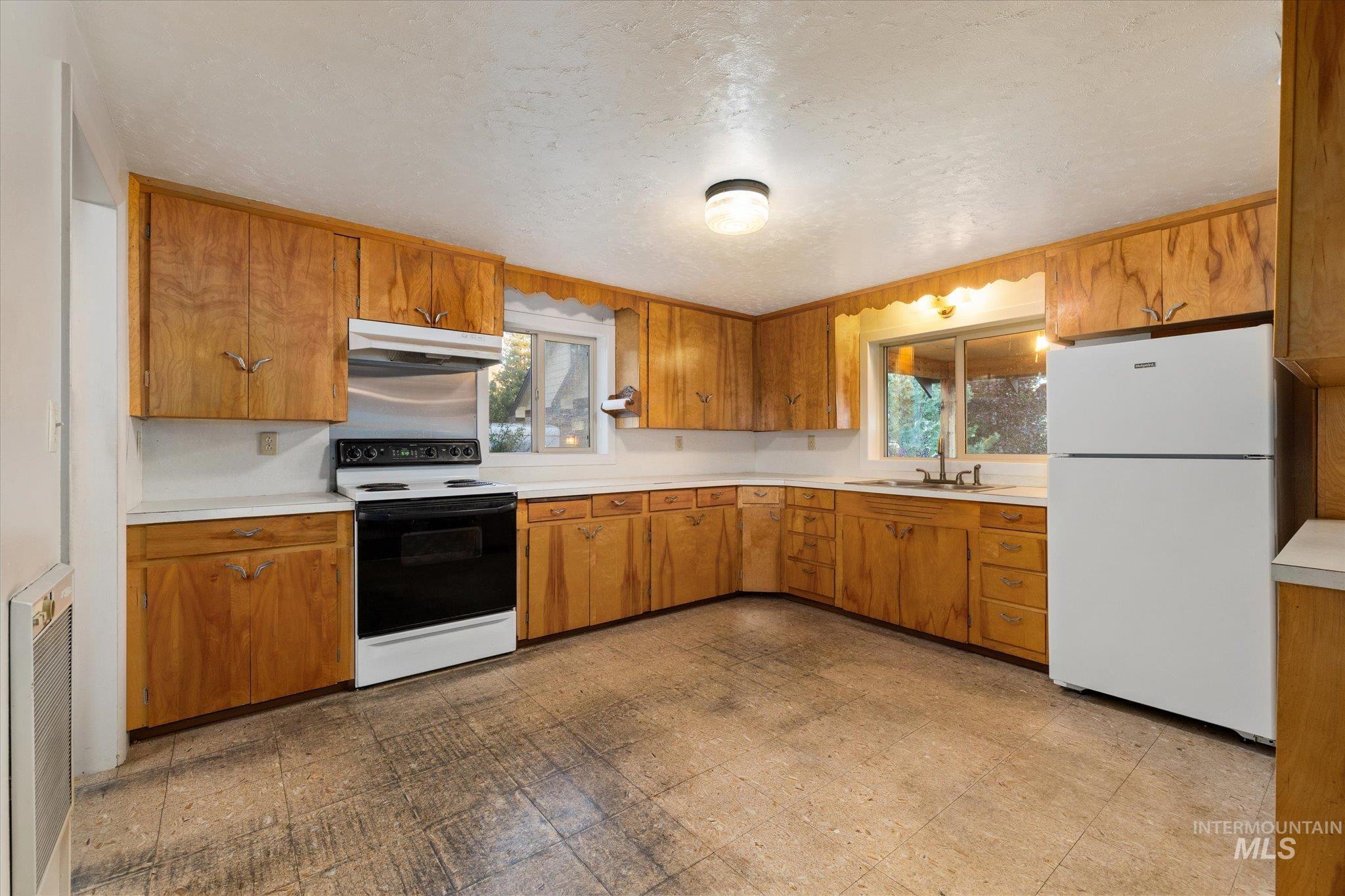 Kitchen featuring extensive wood cabinetry, white countertops, and a double basin sink