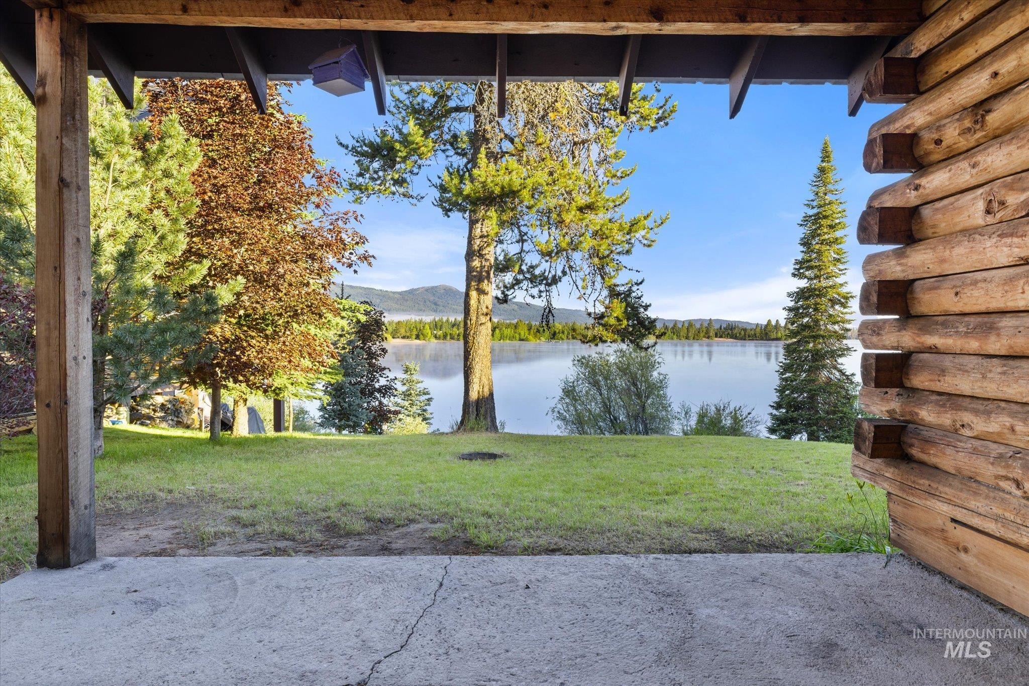 Expansive waterfront lawn featuring mature trees and mountain scenery