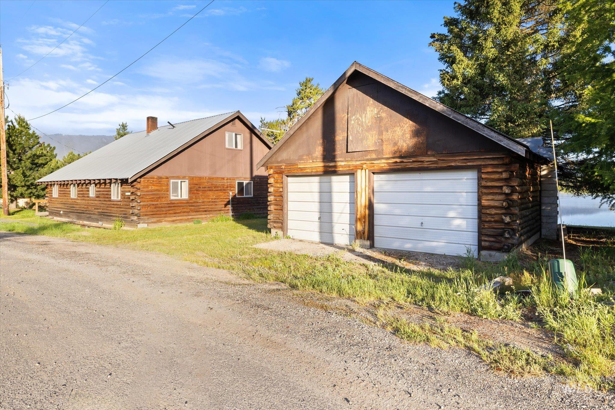 Two-car garage with white panel doors and log-style construction