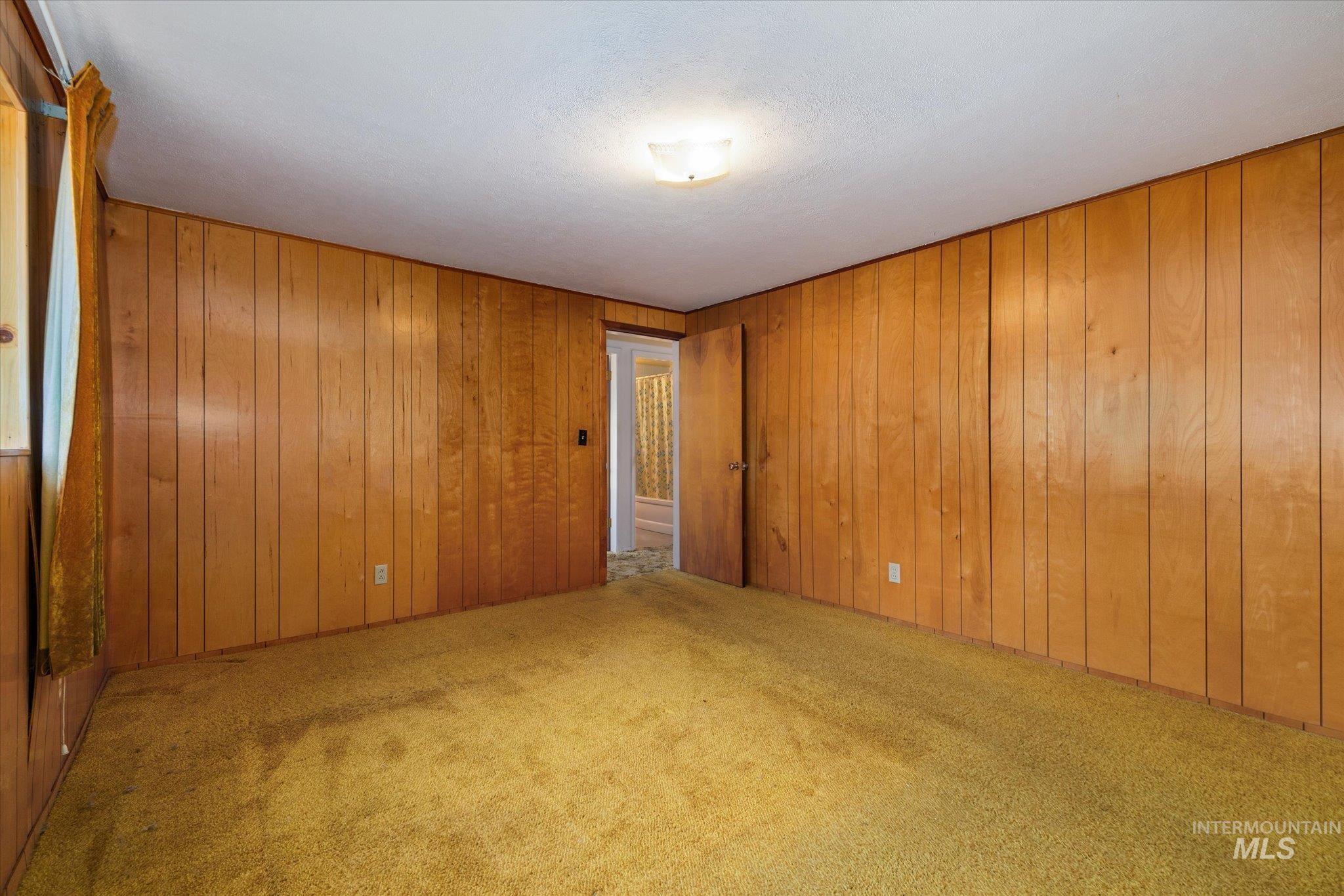 Room featuring wood paneling on walls and a textured carpet