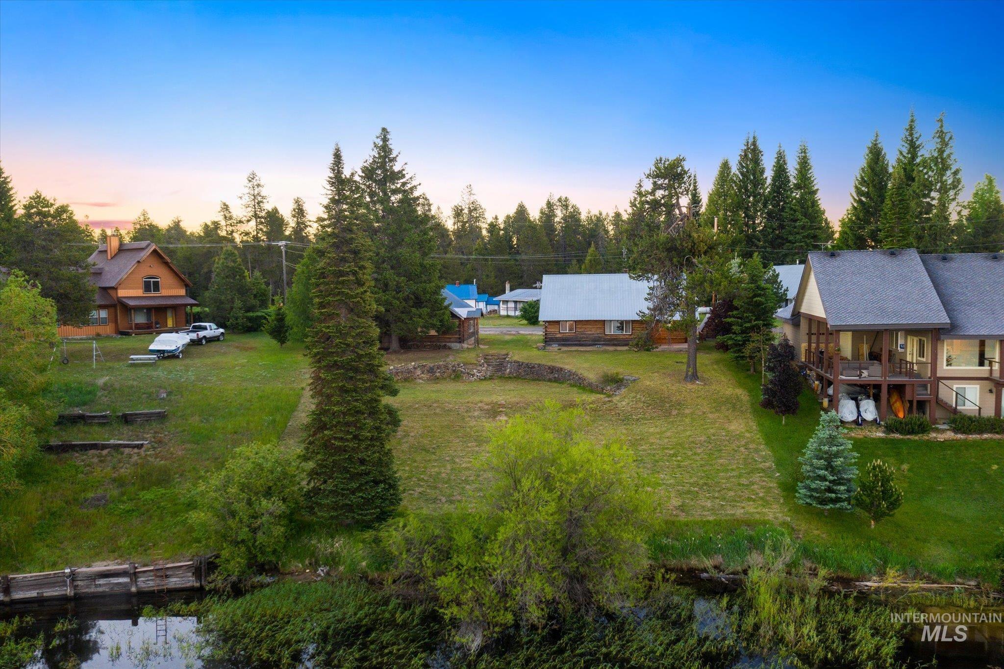 Expansive property featuring a waterfront boundary, mature evergreen trees, and a substantial grassy area