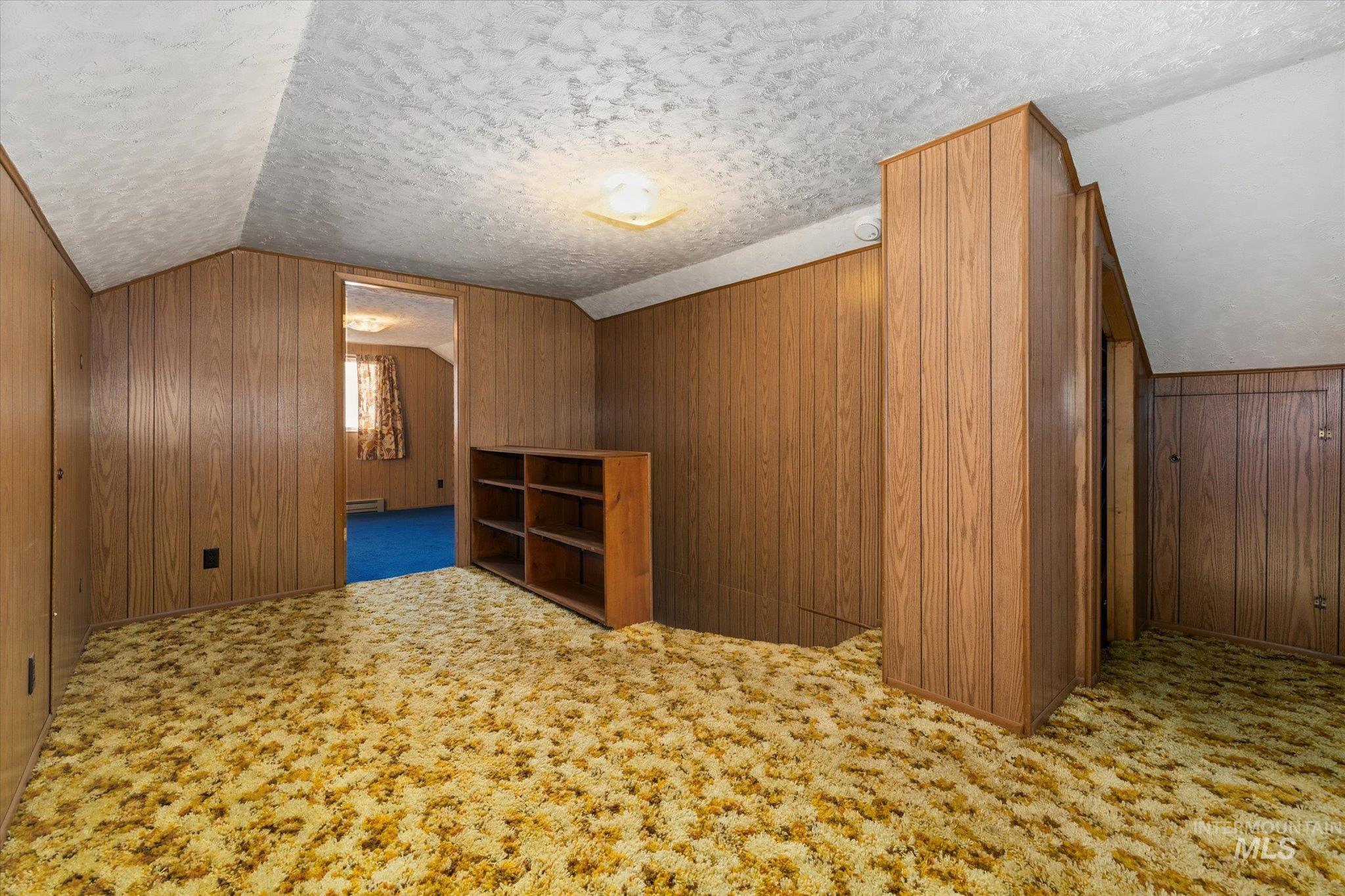 Room featuring wood paneling, textured ceiling, and patterned carpet