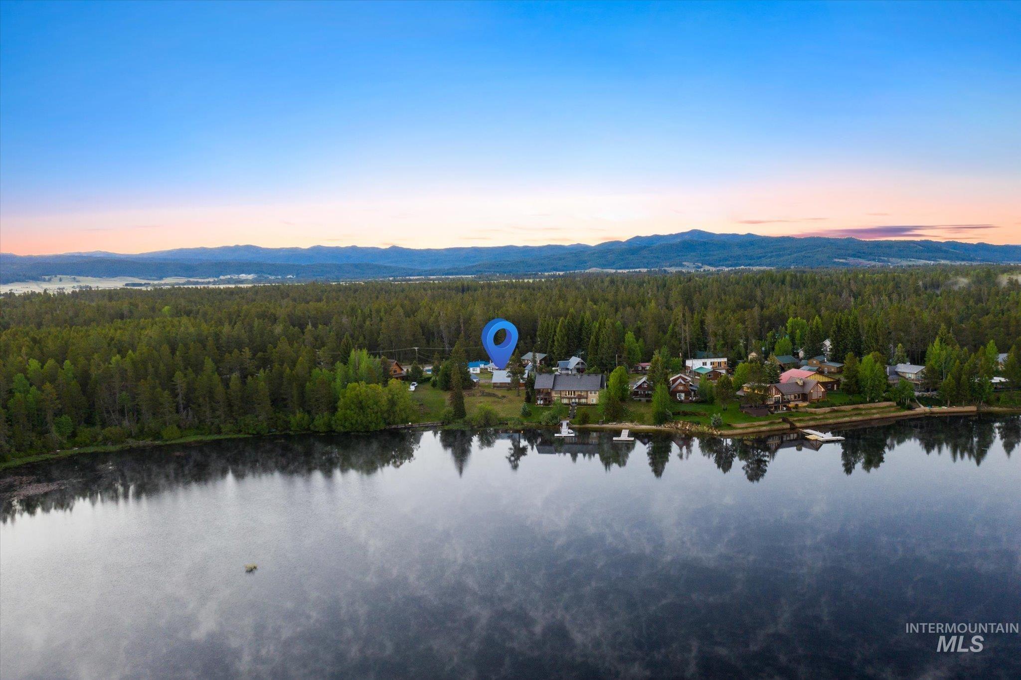 Waterfront property featuring a wooded setting, surrounding mountains, and water access with a dock