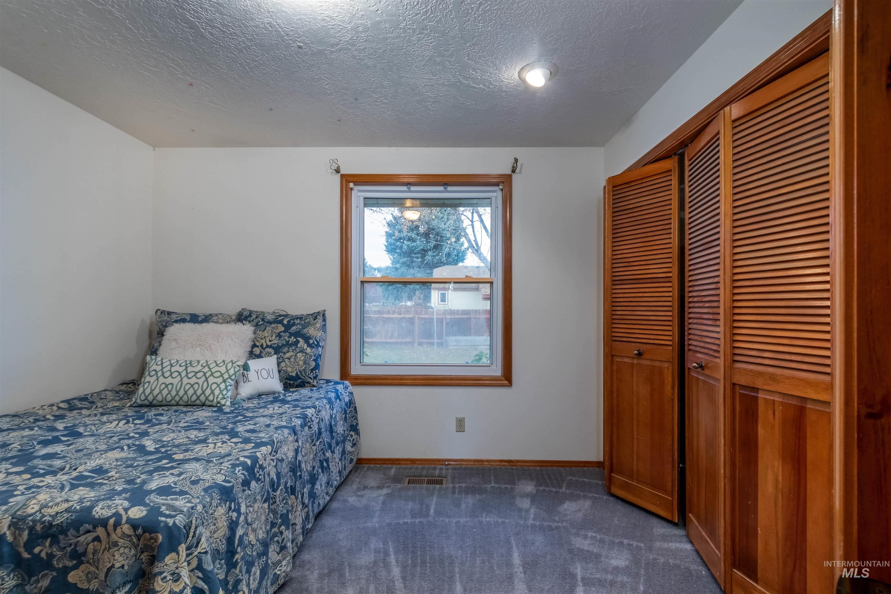 Bedroom featuring dark carpet, a textured ceiling, and a closet