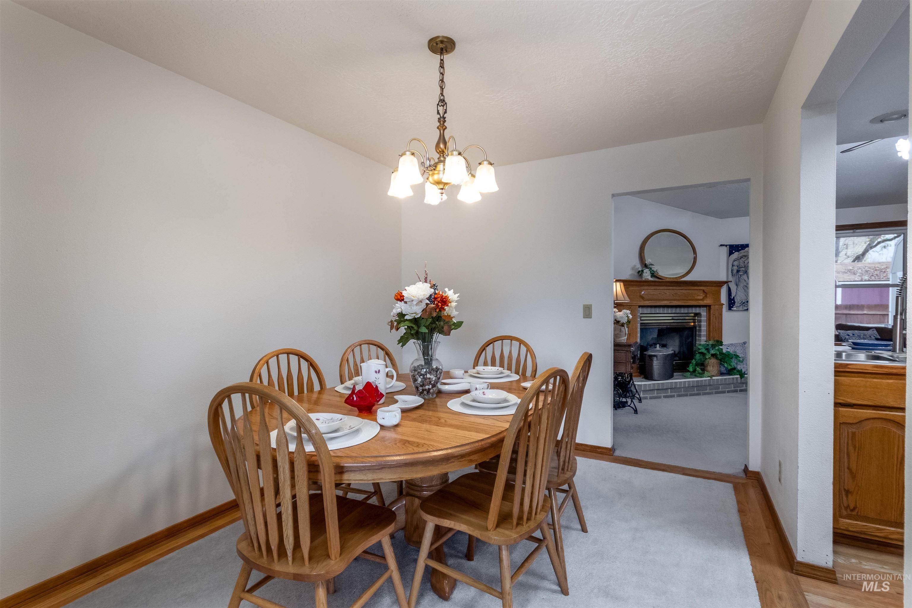 Dining room with a brick fireplace, light wood-style floors, and a chandelier