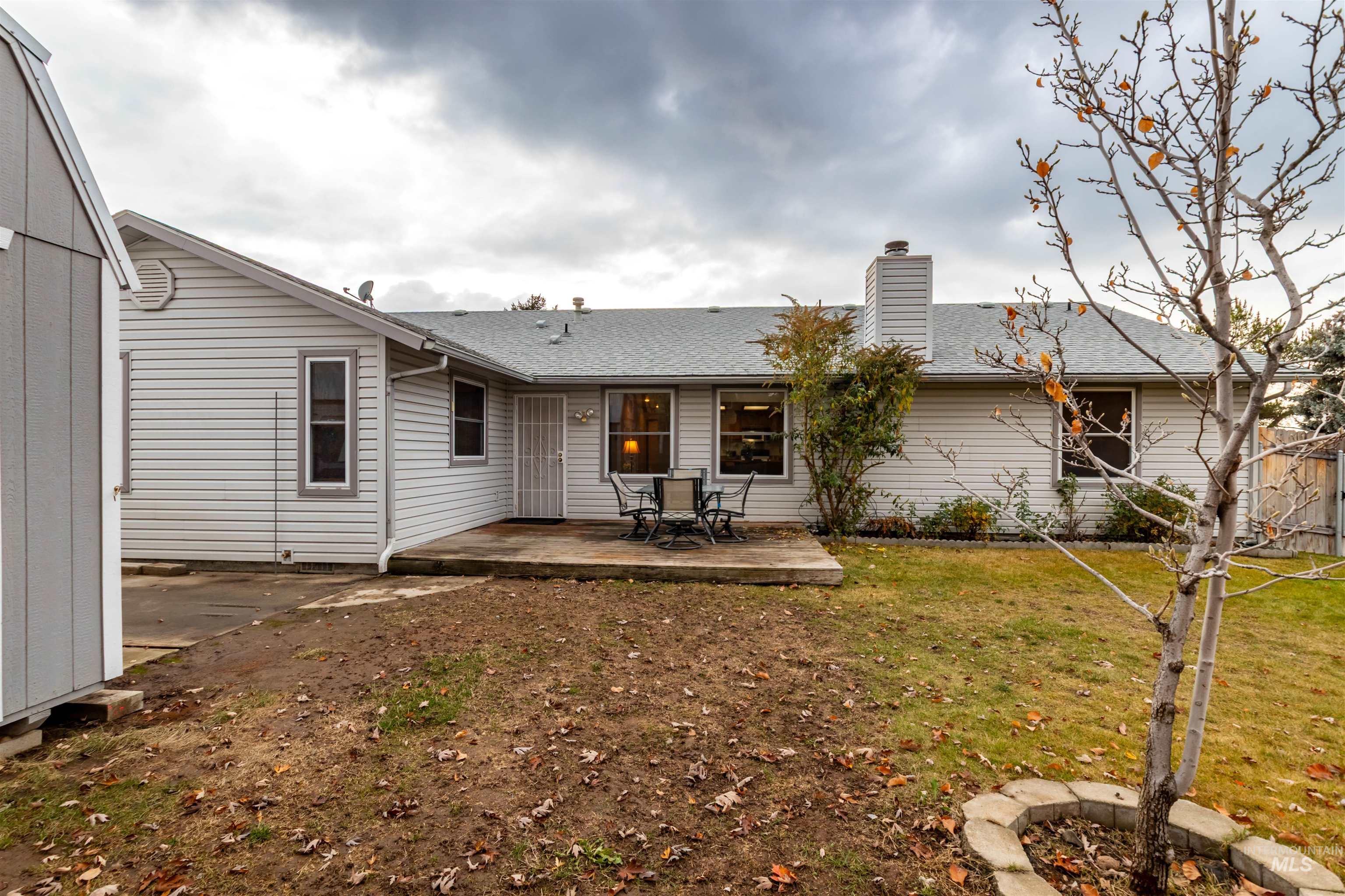 Rear view of property with a shingled roof, a lawn, a patio area, and a chimney