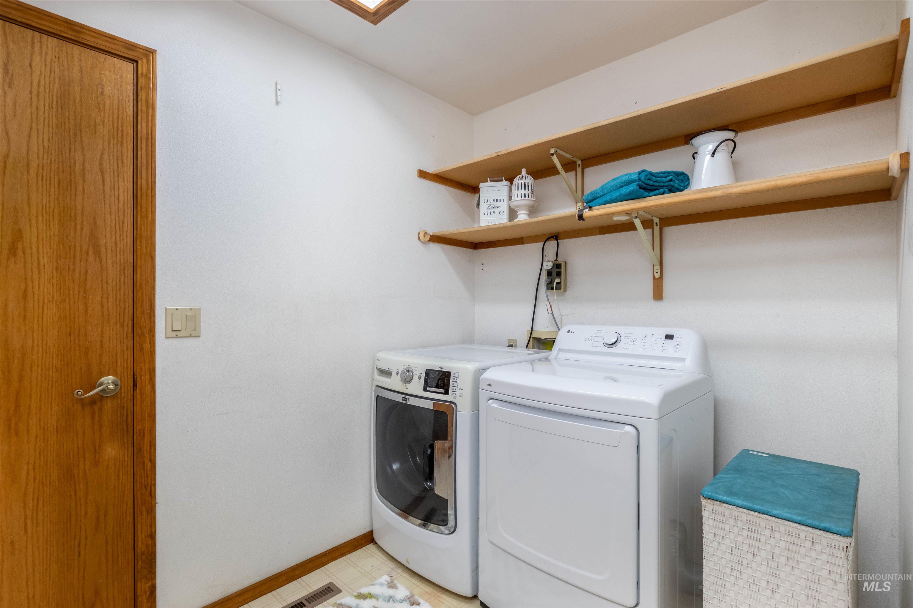 Laundry room featuring washing machine and dryer and baseboards