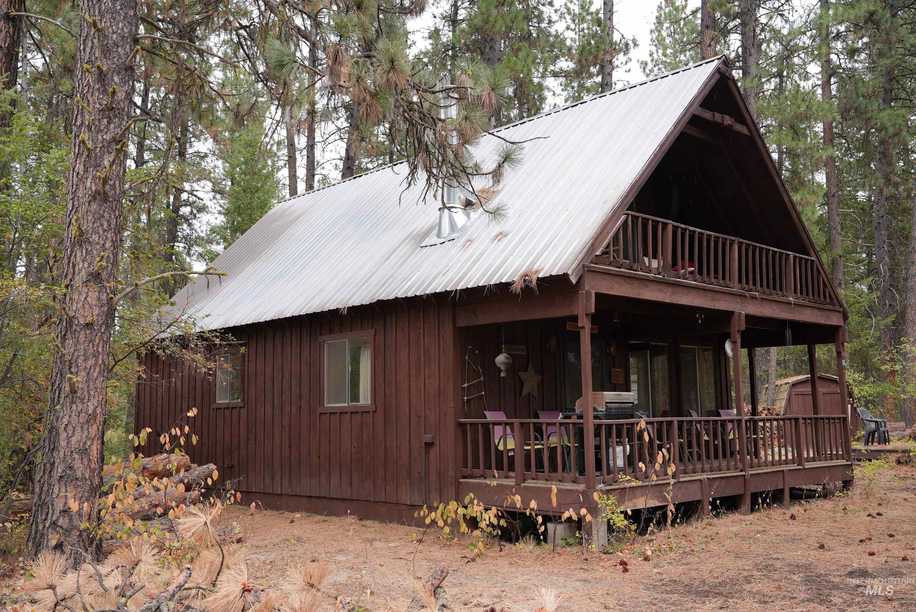 View of front of home with a metal roof, a wooden deck, and an outdoor structure