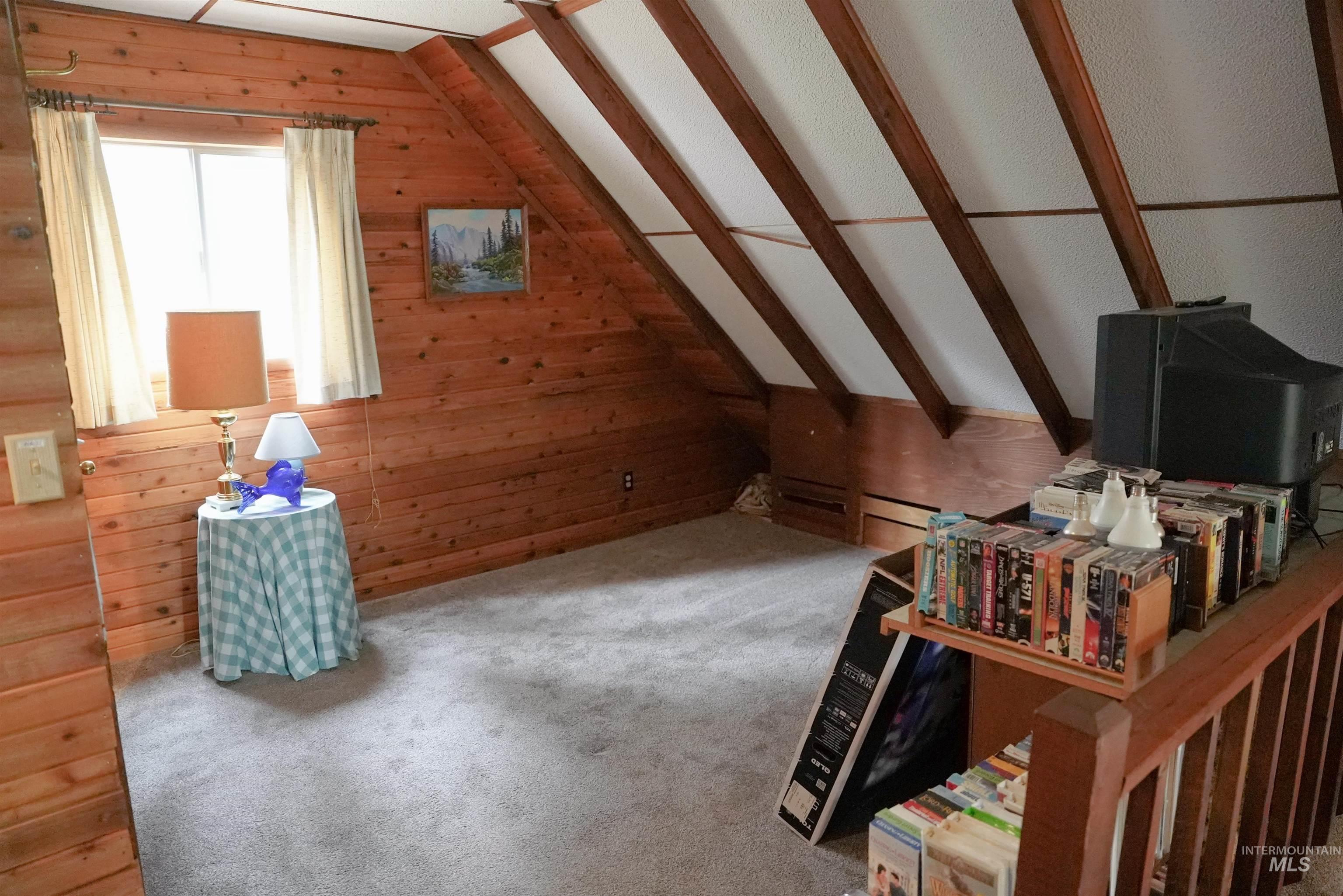 Bonus room featuring wood walls, carpet, and vaulted ceiling