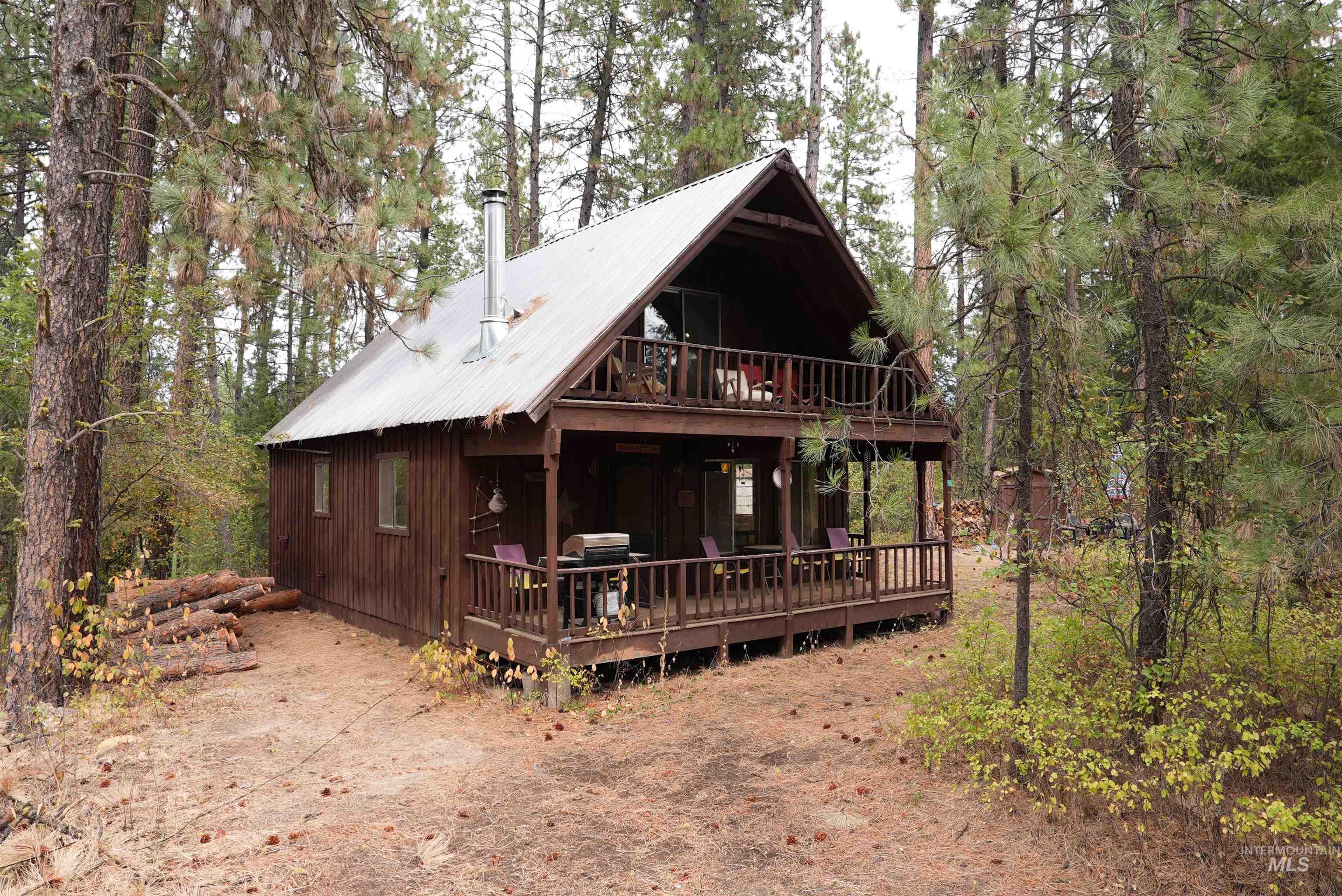 Chalet / cabin featuring a metal roof, a wooded view, and a deck