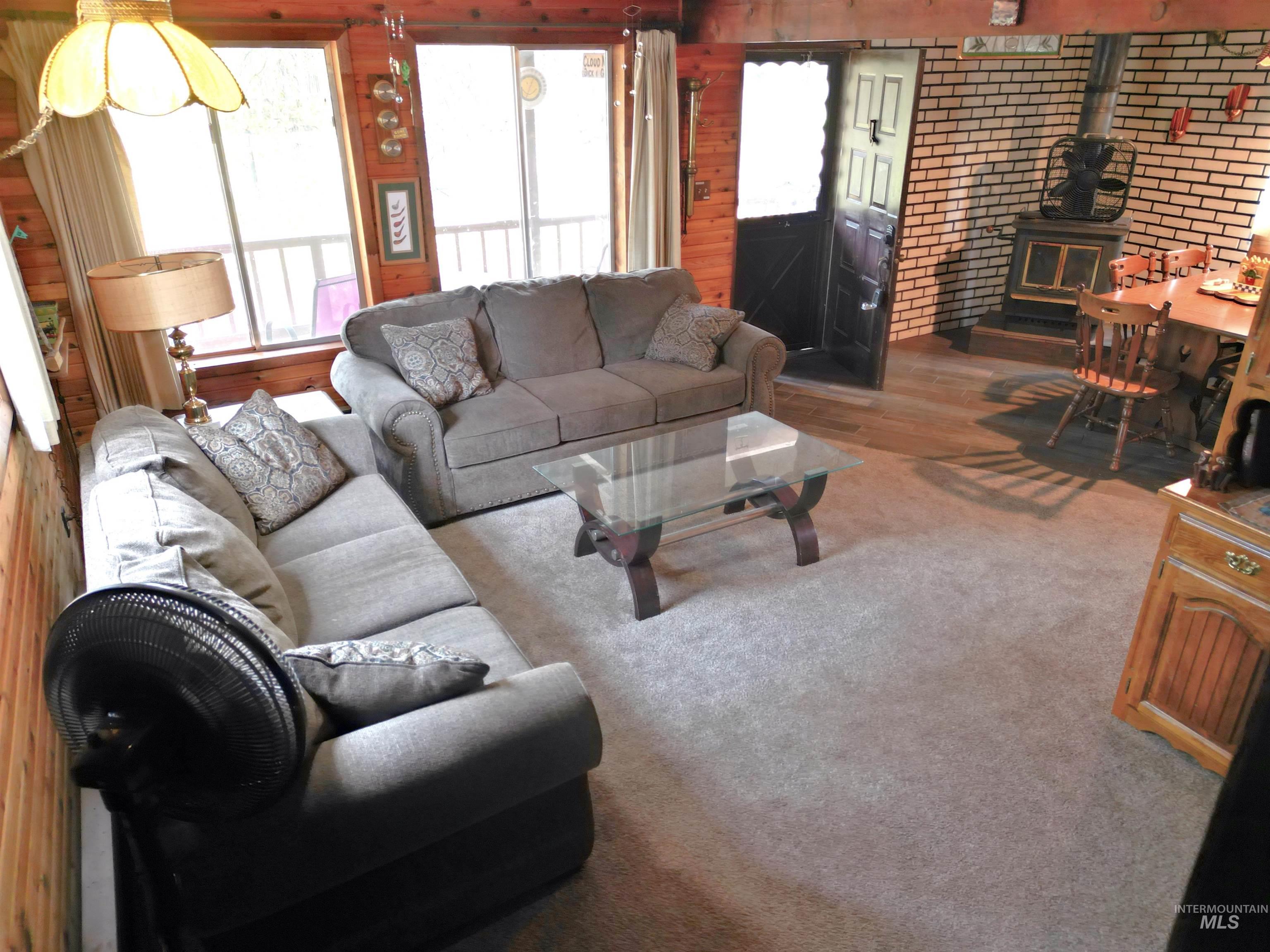 Living area with a wood stove, plenty of natural light, carpet floors, and brick wall
