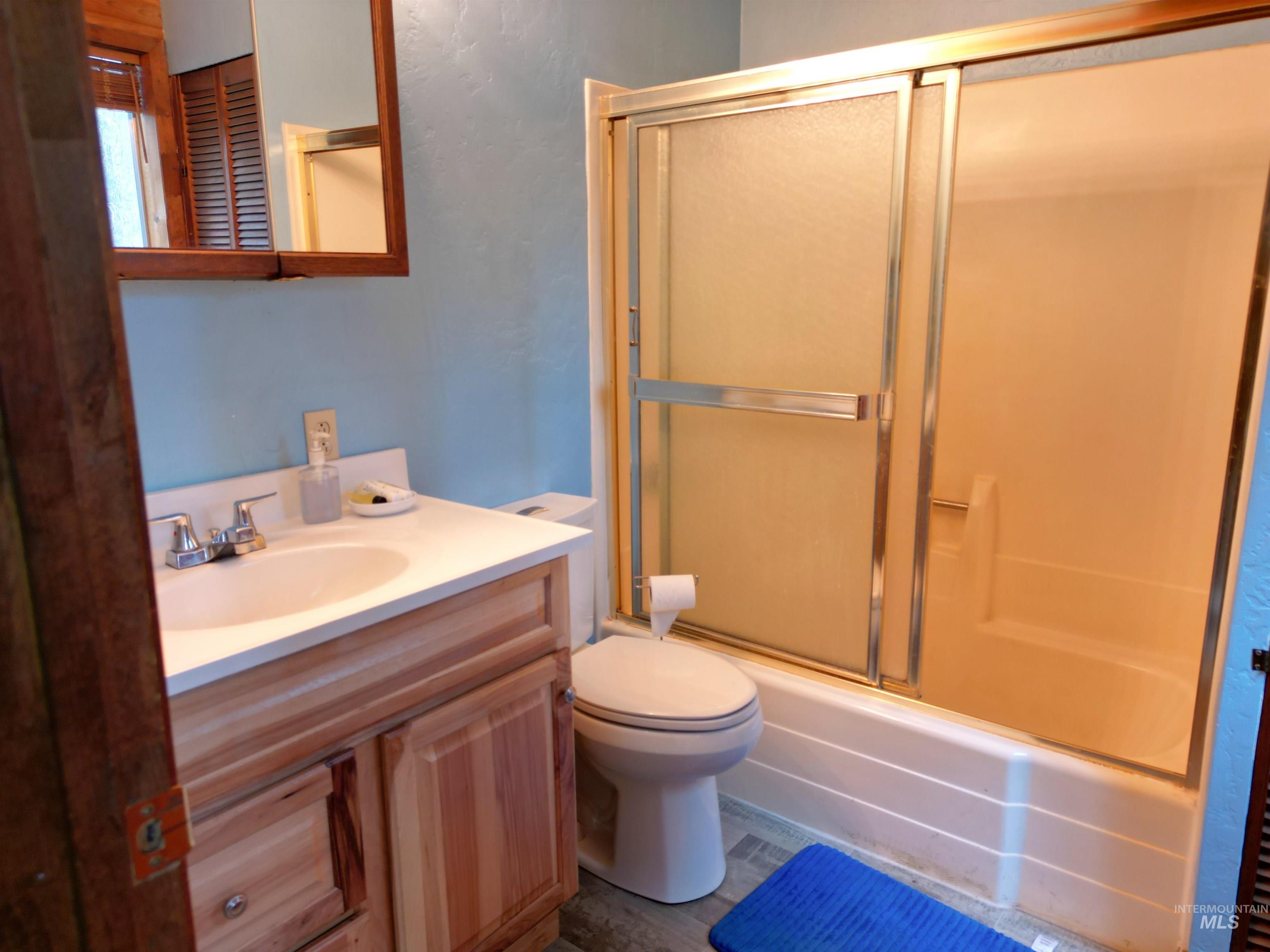 Full bath featuring bath / shower combo with glass door and vanity